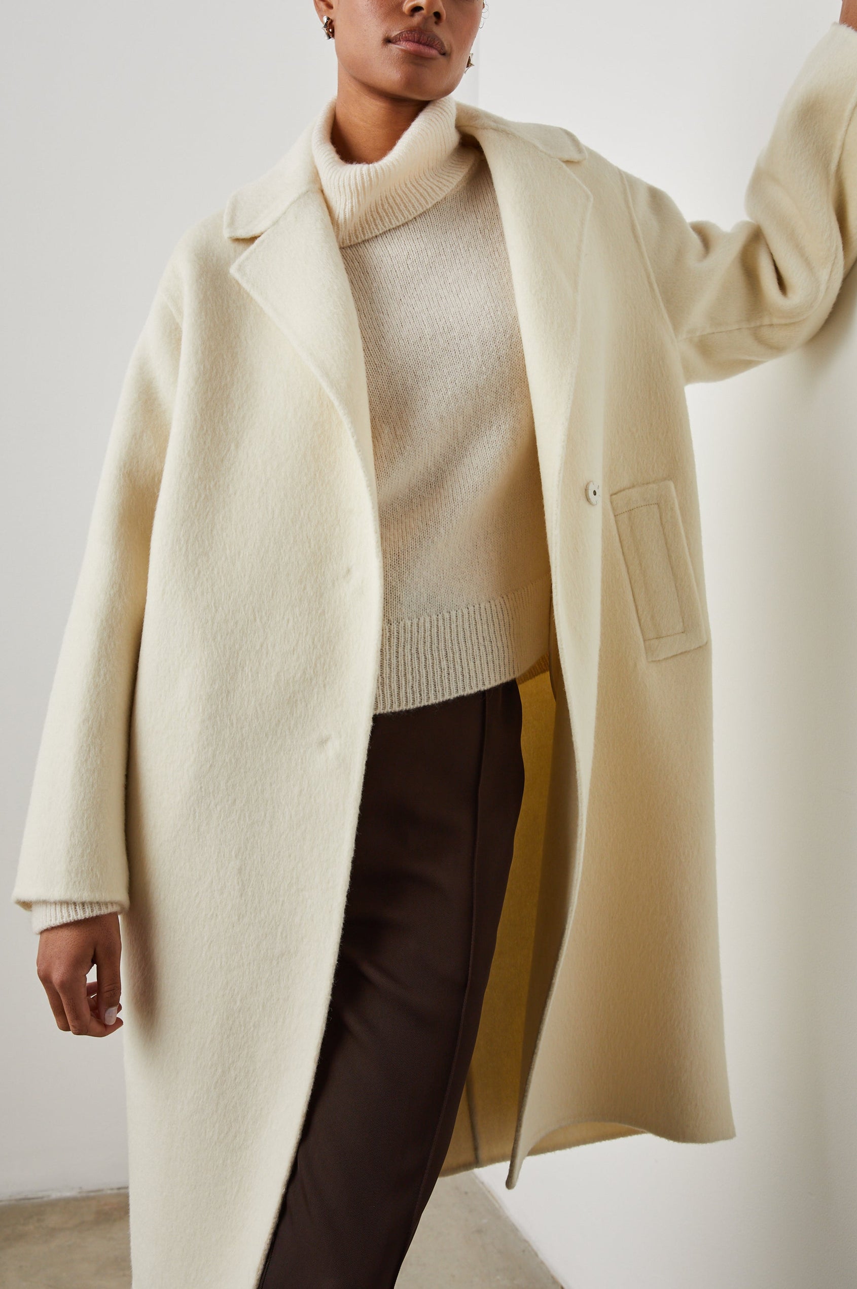Lore Knee-Length Coat with Two Button Closure, Notched Lapels and Two Front Pockets in Ivory Colorway - Front View Featured on Model