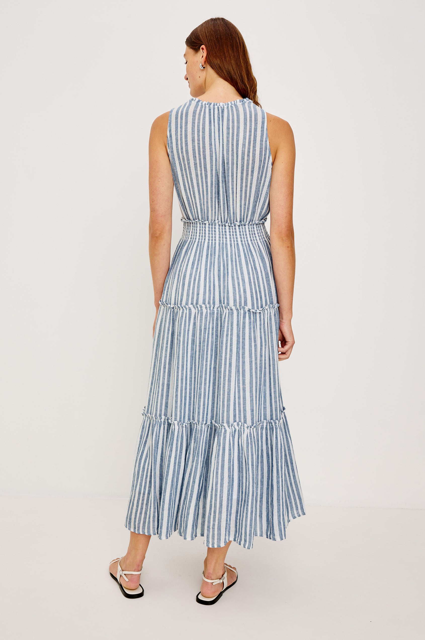 Loulou V-Neck Midi Dress with Smocked Elastic Waistband and a Multi Tiered Skirt in Blue/White Jalisco Stripe Colorway. Full Body Back View Shown on Model.