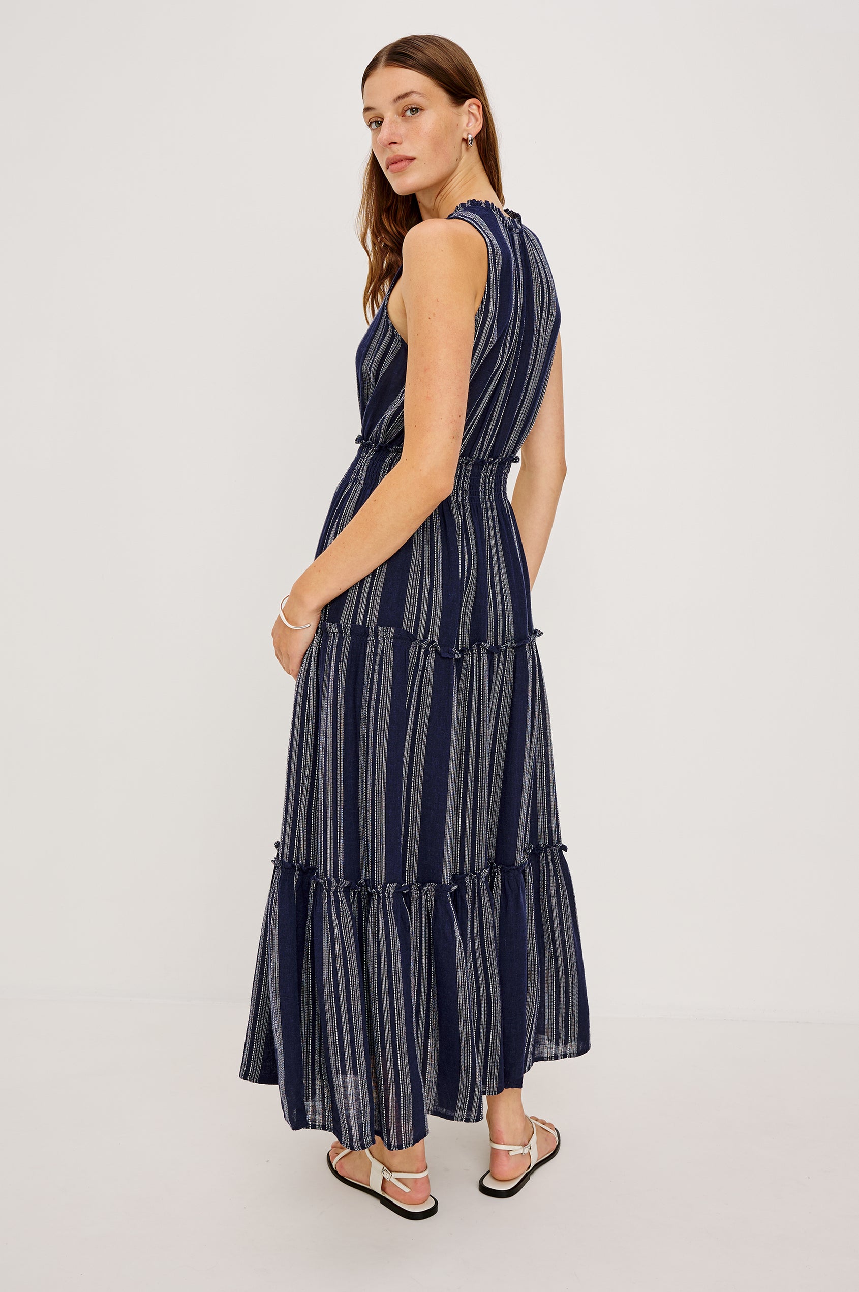 Loulou V-Neck Midi Dress with Smocked Elastic Waistband and a Multi Tiered Skirt in navy blue Magalia Stripe Colorway. Full Body Side View Shown on Model.