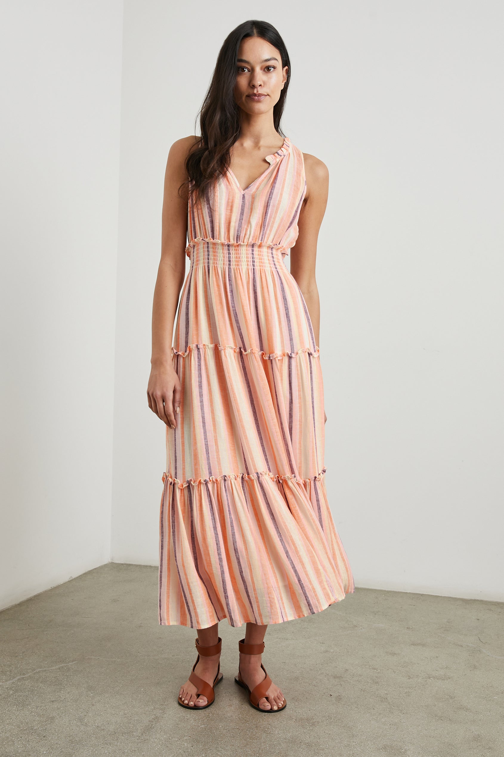 Loulou Sleeveless Midi Dress with a V Neck, Shirred Collar, Smocked Waist and Tiered Skirt in Papaya Stripe Colorway, purple, oranges and cream vertical Stripes - Front Full Body View Featured on Model