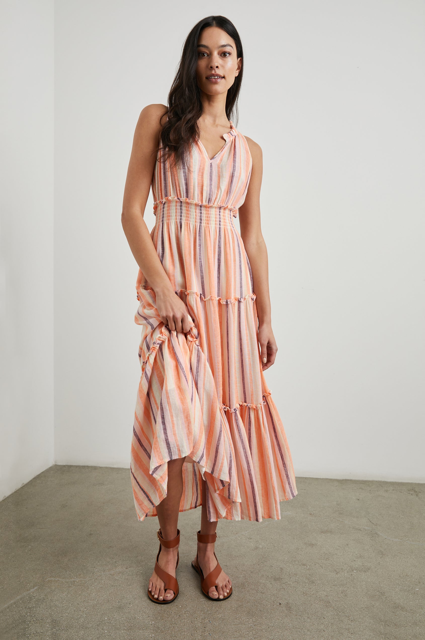 Loulou Sleeveless Midi Dress with a V Neck, Shirred Collar, Smocked Waist and Tiered Skirt in Papaya Stripe Colorway, purple, oranges and cream vertical Stripes - Front Full Body View Featured on Model