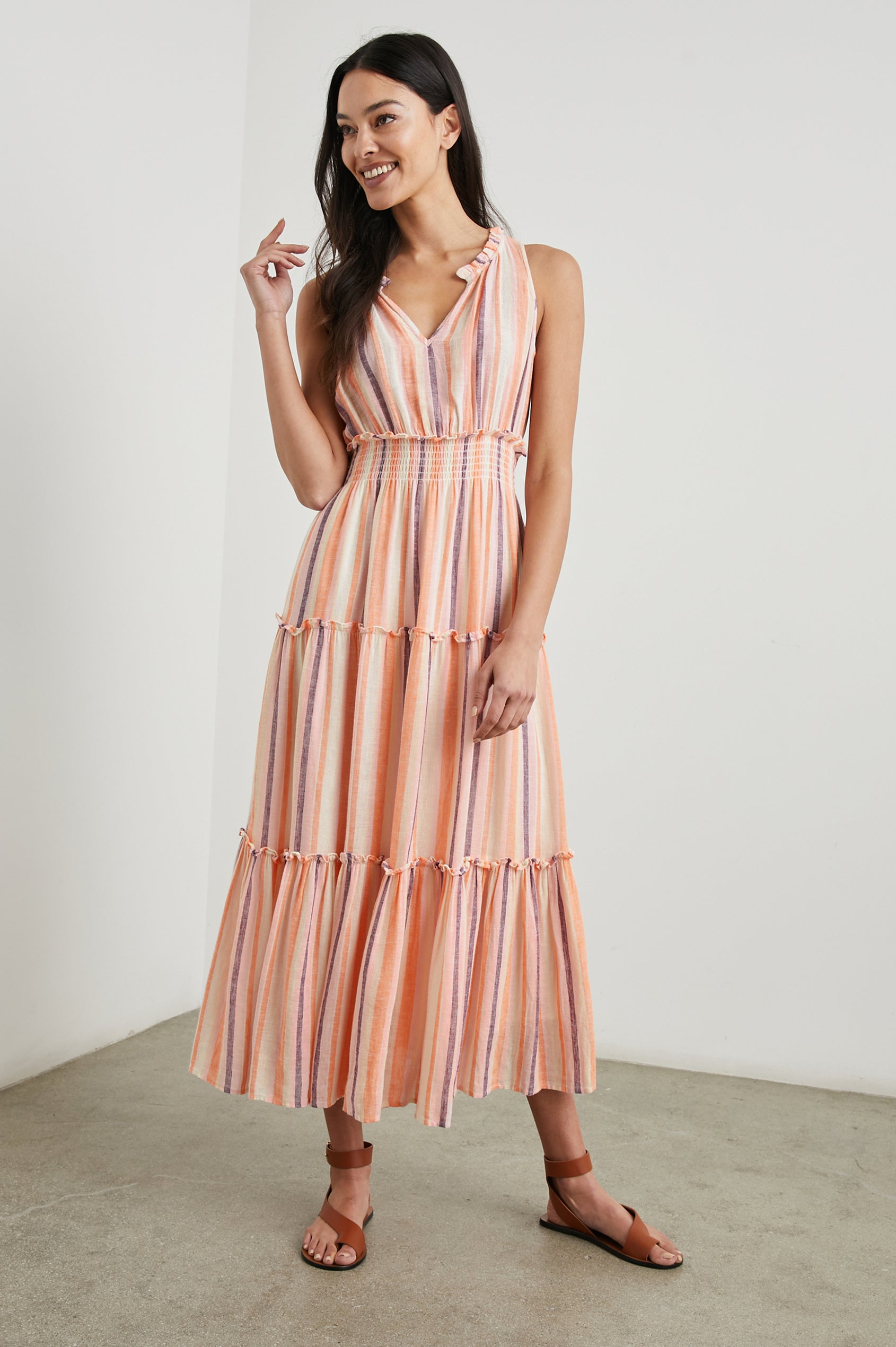 Loulou Sleeveless Midi Dress with a V Neck, Shirred Collar, Smocked Waist and Tiered Skirt in Papaya Stripe Colorway, purple, oranges and cream vertical Stripes - Front Full Body View Featured on Model