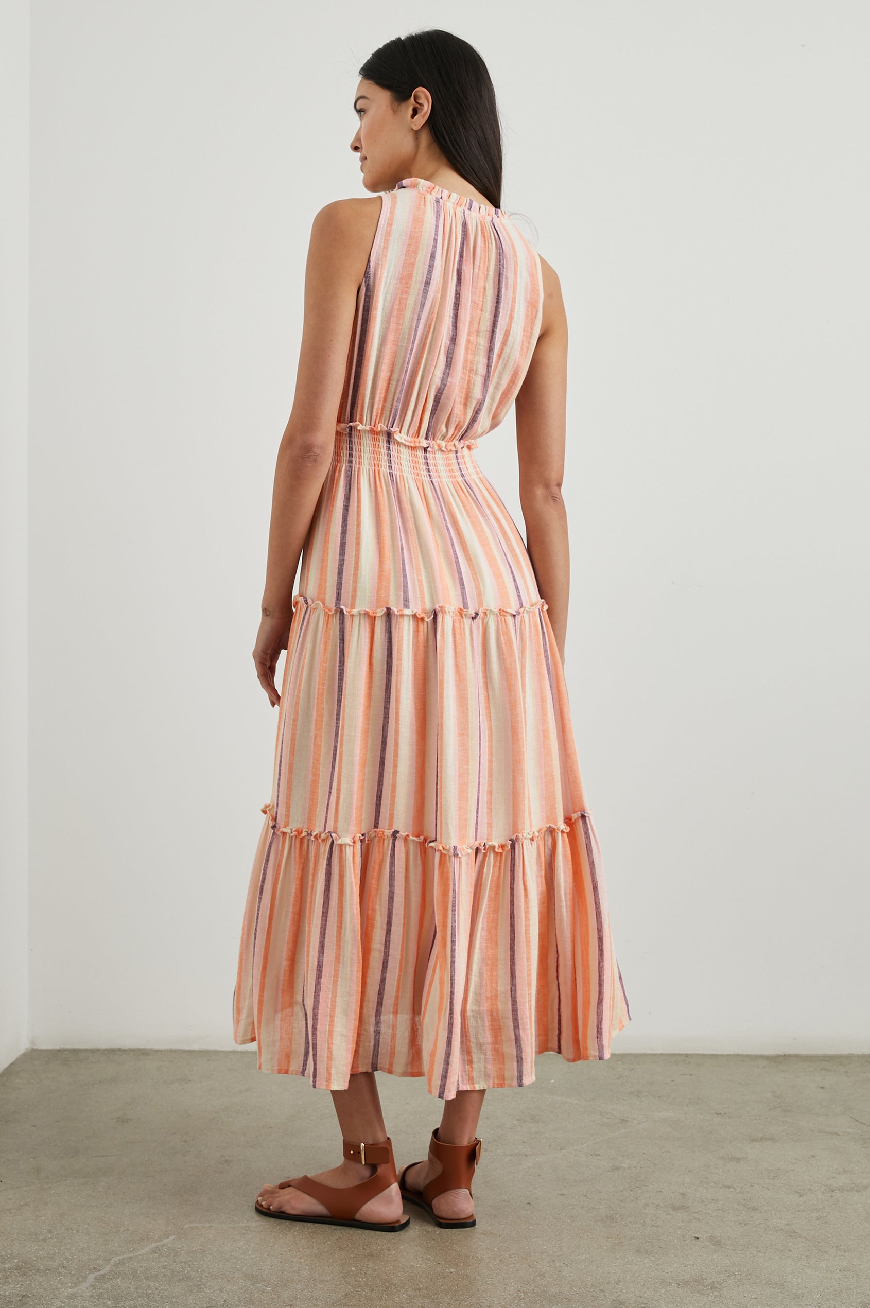 Loulou Sleeveless Midi Dress with a V Neck, Shirred Collar, Smocked Waist and Tiered Skirt in Papaya Stripe Colorway, purple, oranges and cream vertical Stripes - Back Full Body View Featured on Model