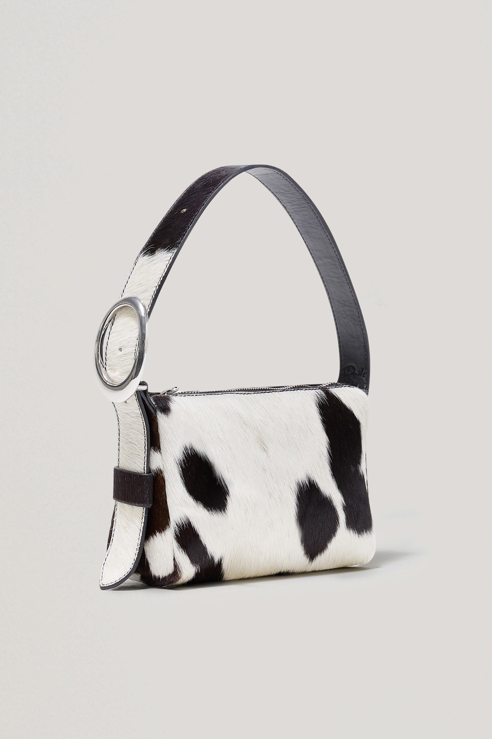 The Lucca is a long-hair cowhide shoulder bag with an adjustable strap and polished silver oval buckle. In Cowgirl Haircalf colorway. Front view featured.