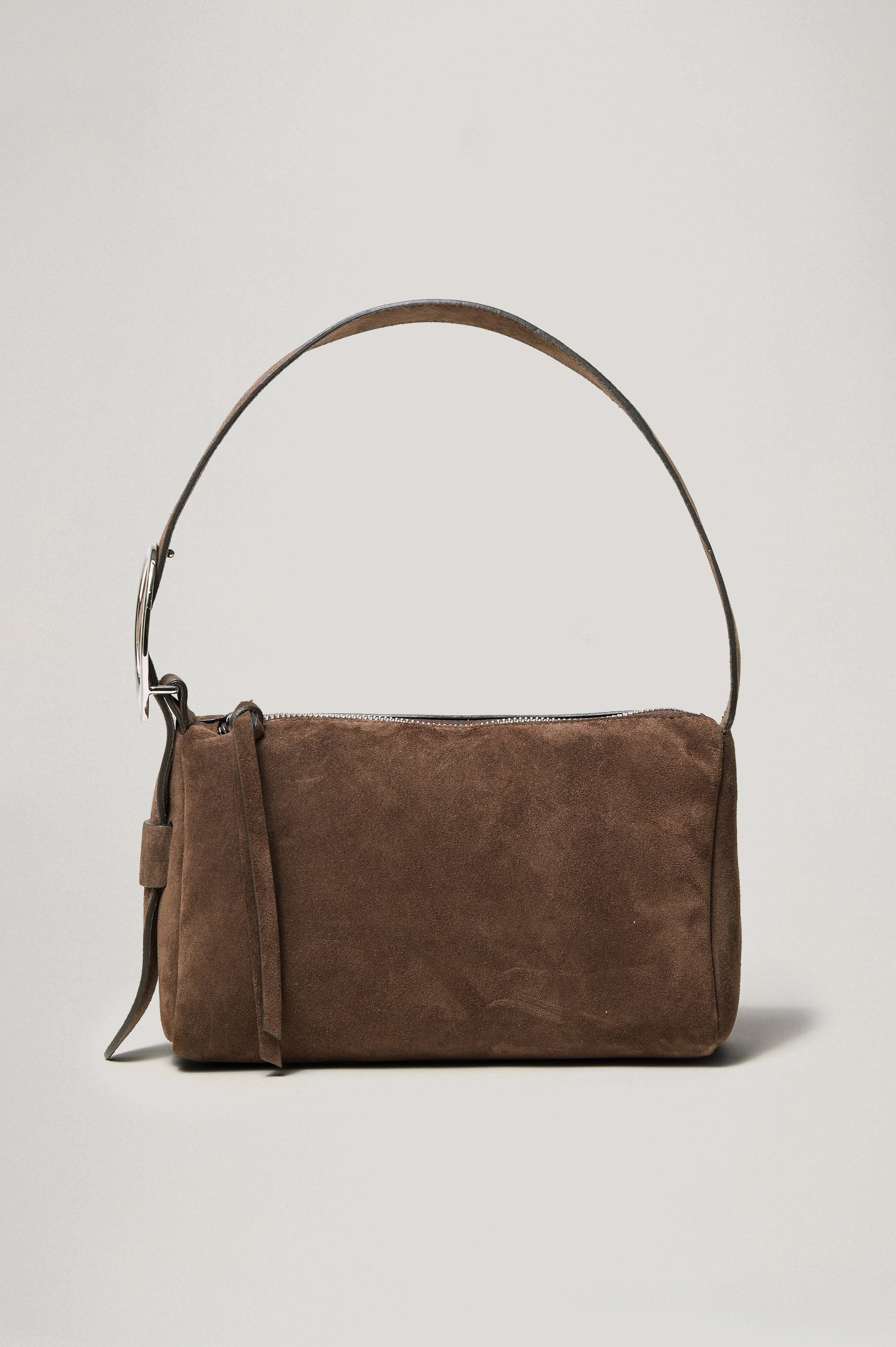 The Lucca is a smooth suede shoulder bag with an adjustable strap and polished silver oval buckle. In Espresso Suede colorway. Front view featured.