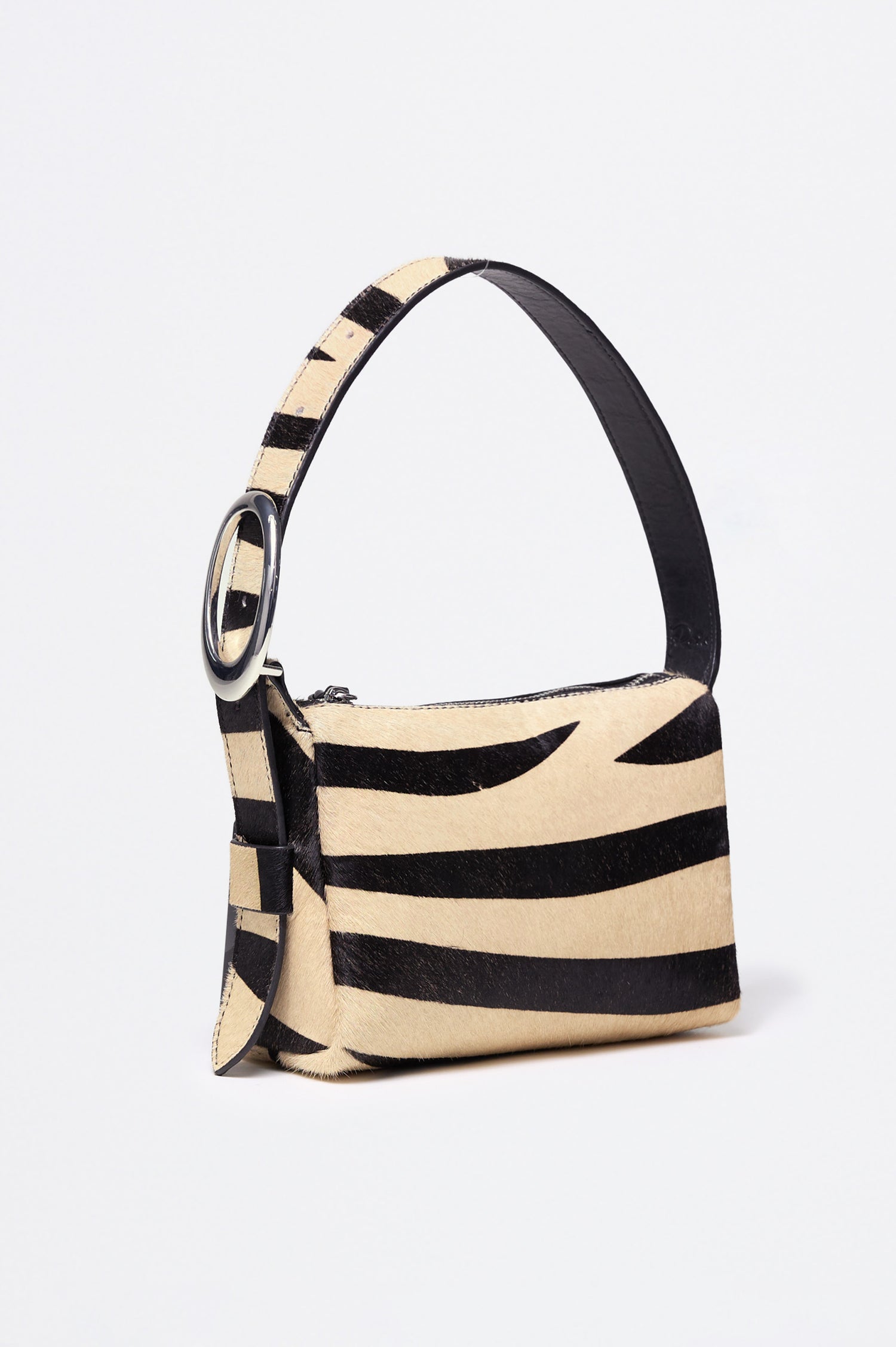 The Lucca is a long-hair cowhide shoulder bag with an adjustable strap and polished silver oval buckle. In Zebra Haircalf colorway. Front view featured.