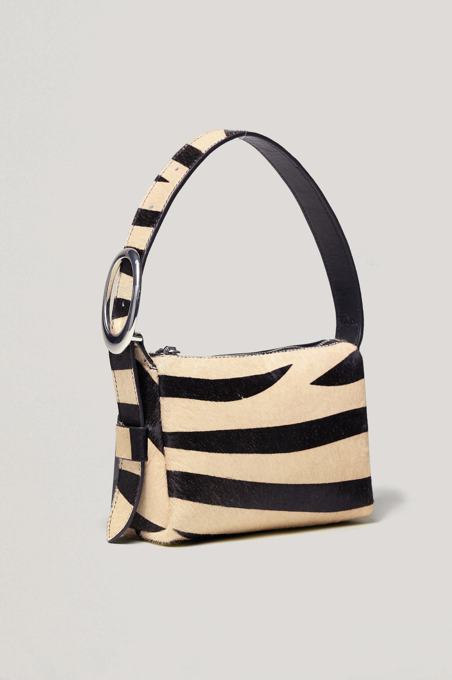 The Lucca is a long-hair cowhide shoulder bag with an adjustable strap and polished silver oval buckle. In Zebra Haircalf colorway. Front view featured.