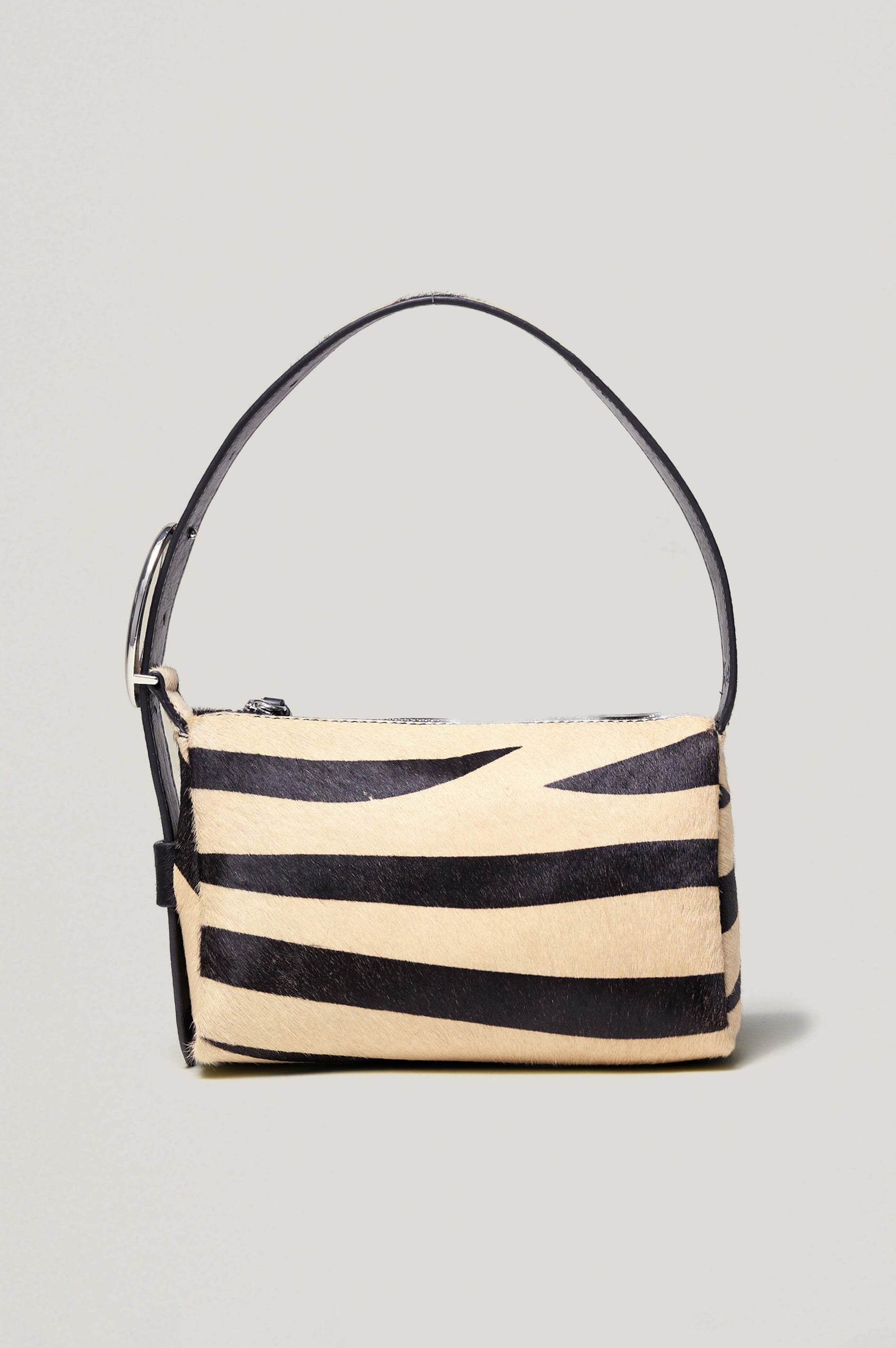 The Lucca is a long-hair cowhide shoulder bag with an adjustable strap and polished silver oval buckle. In Zebra Haircalf colorway. Close up view of strap featured.