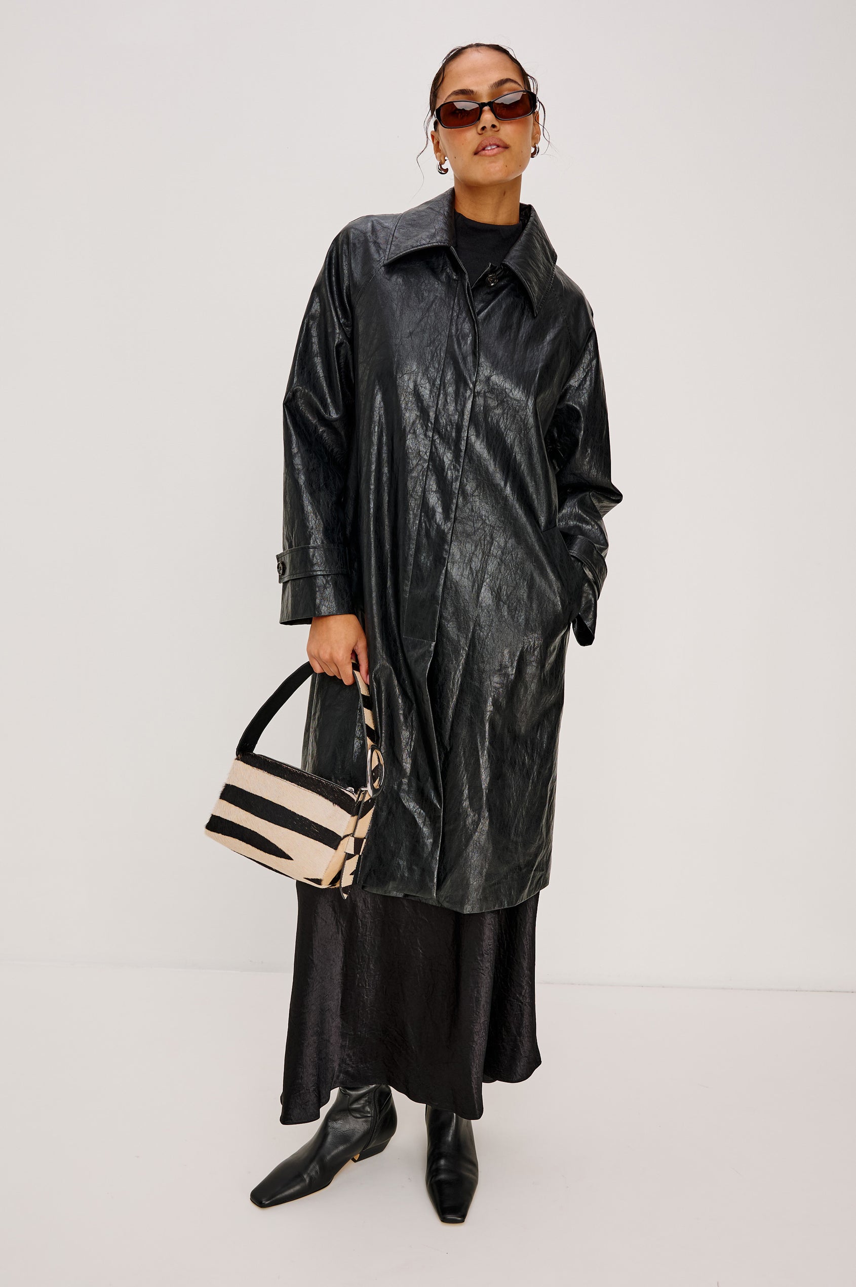 The Lucca is a long-hair cowhide shoulder bag with an adjustable strap and polished silver oval buckle. In Zebra Haircalf colorway. Front view on the model's hand featured.