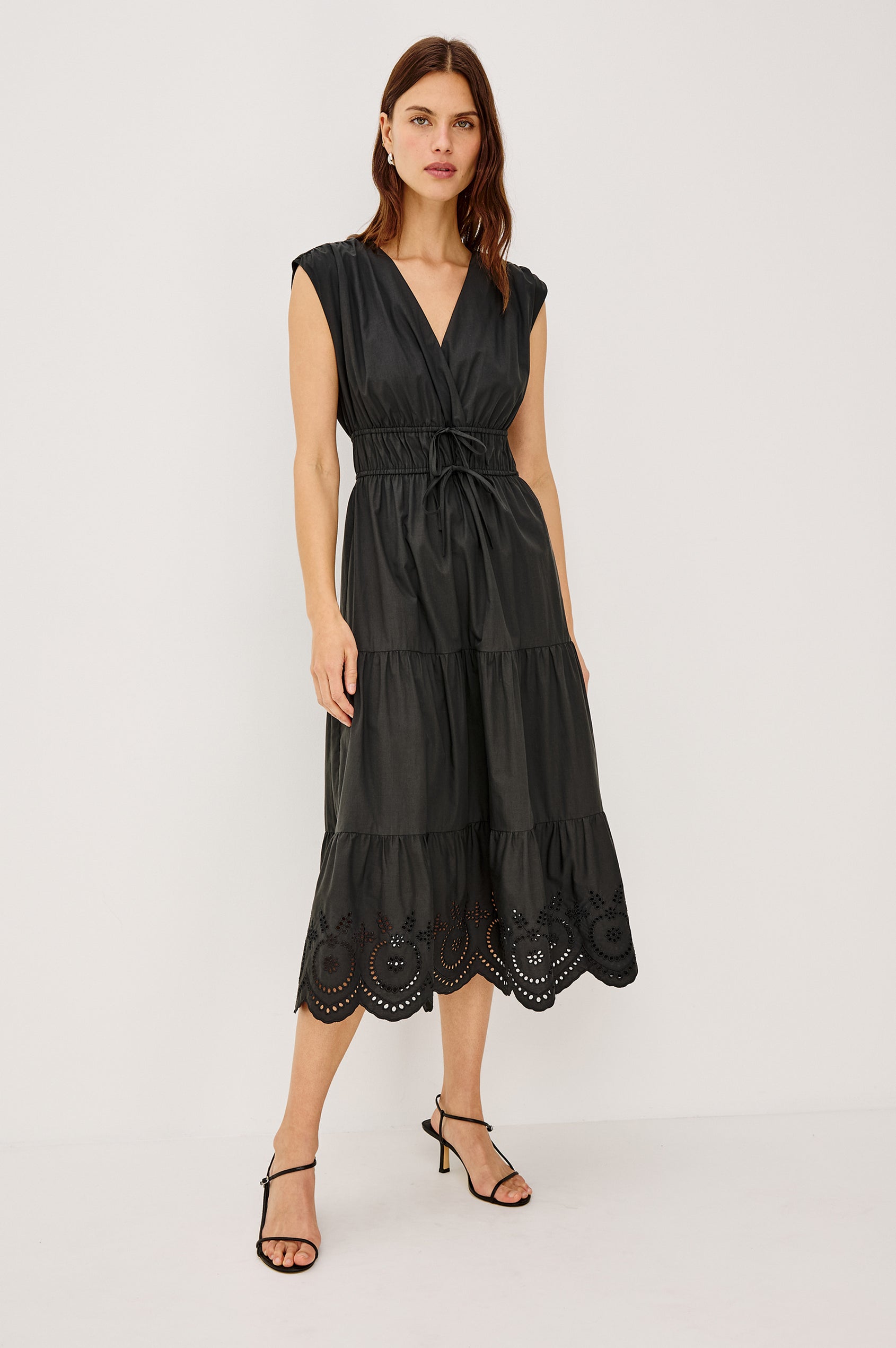 Lucia Midi Dress with Cap Sleeves, a Crossover V neckline, an Elastic Waist with Ties, and a Tiered Skirt in black Colorway - Front Full Body View Featured on Model