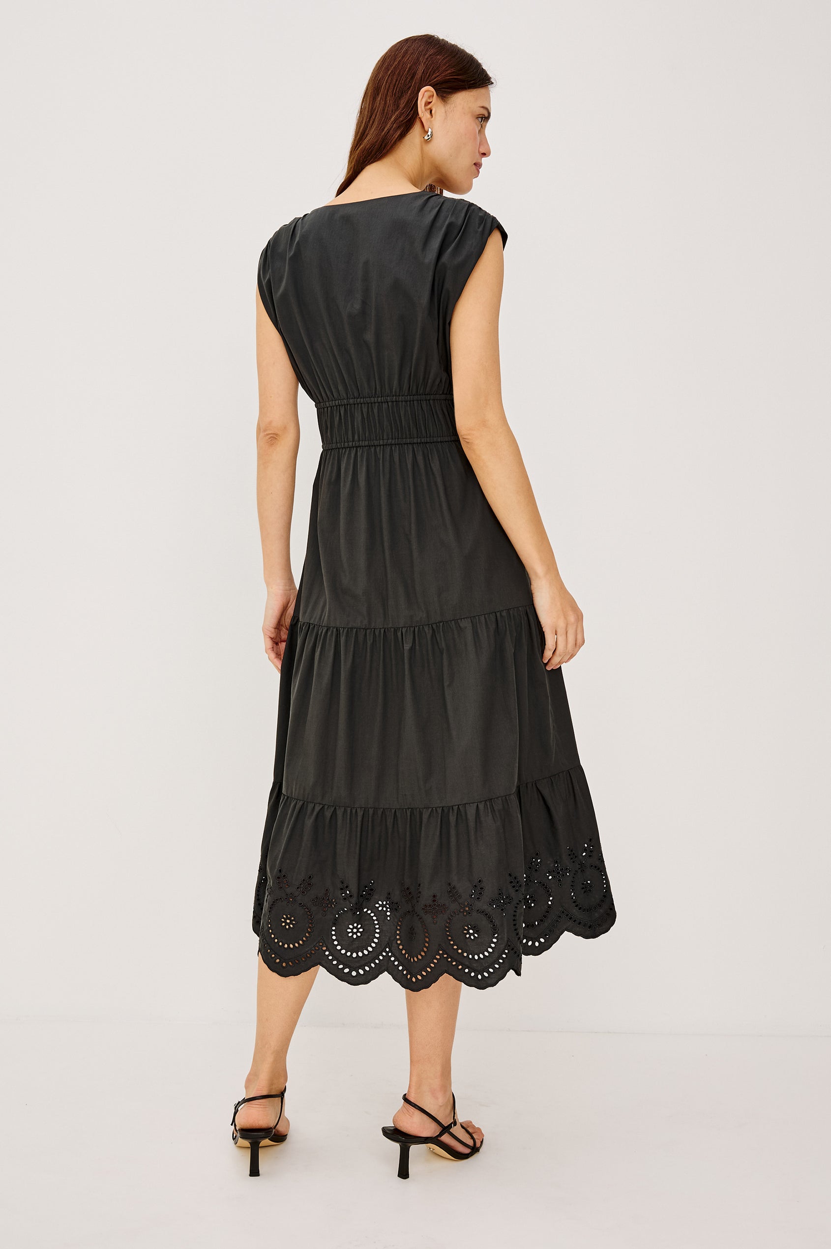 Lucia Midi Dress with Cap Sleeves, a Crossover V neckline, an Elastic Waist with Ties, and a Tiered Skirt in black Colorway - Front Full Body View Featured on Model