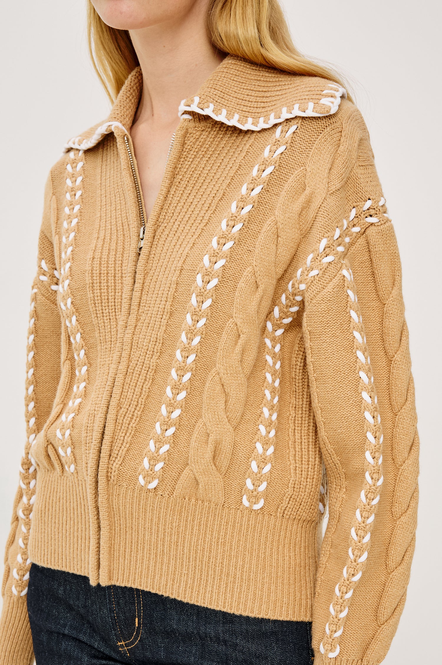 Lune Sweater in Cable Knit With Contrast Blanket Stitch Detailing, Stand Collar, Front Zipper, and Long Sleeves in Camel Ivory Blanket Stitch Colorway - Upper Body Close Up View Featured on Model