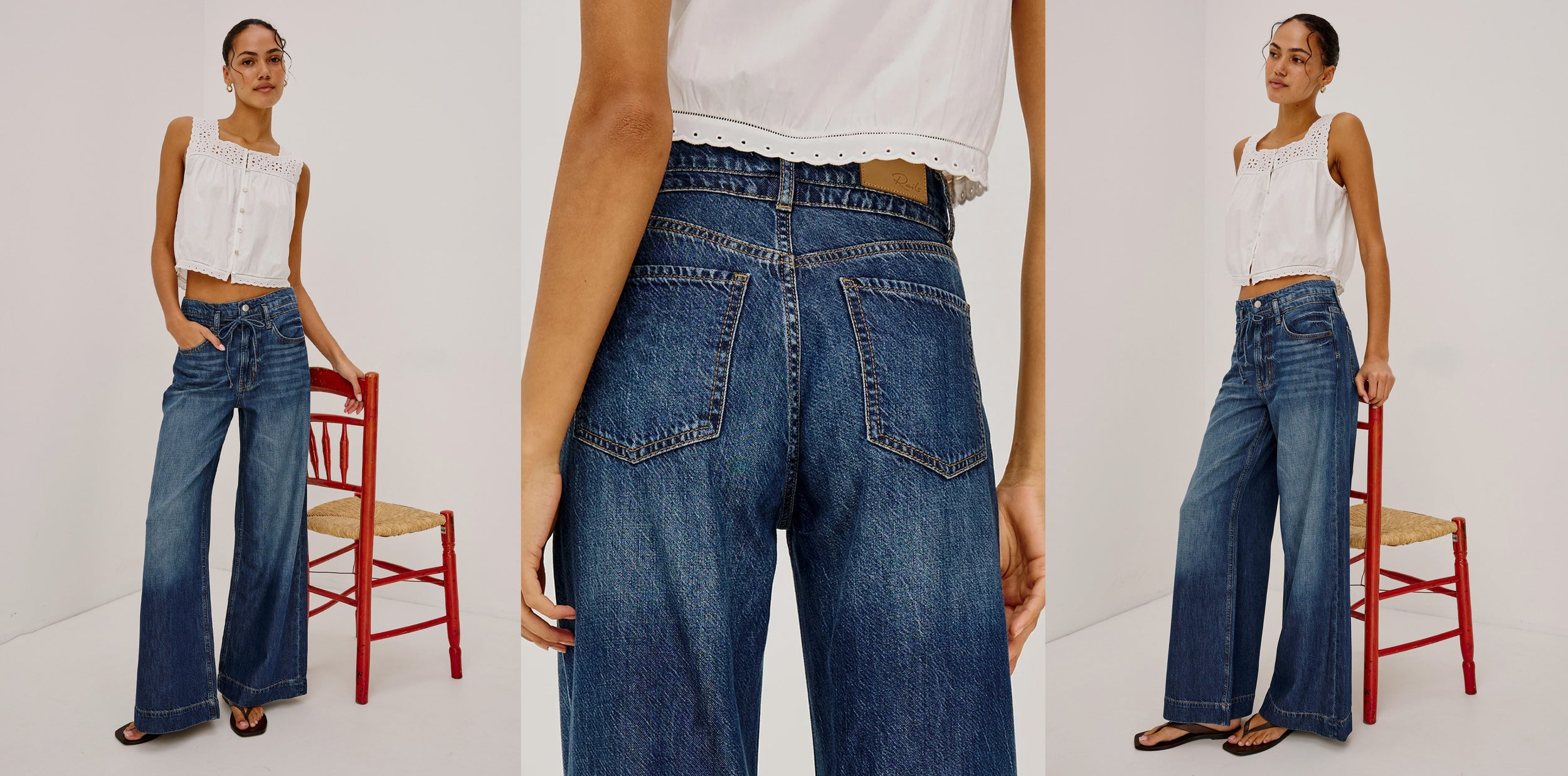 Woman wearing blue jeans and a white top, standing next to a red chair on a white background.