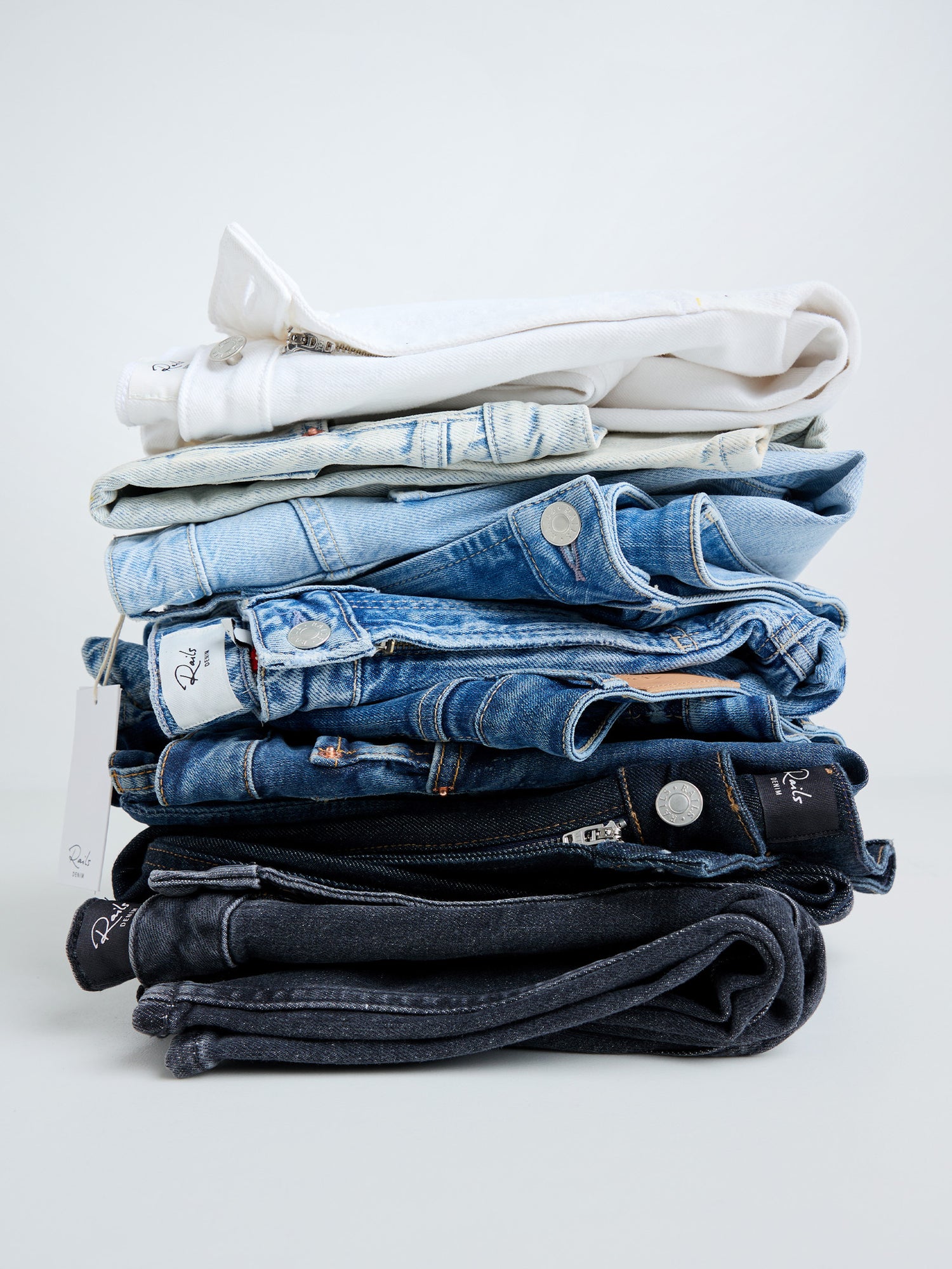 Stack of folded jeans and shirts on a white background