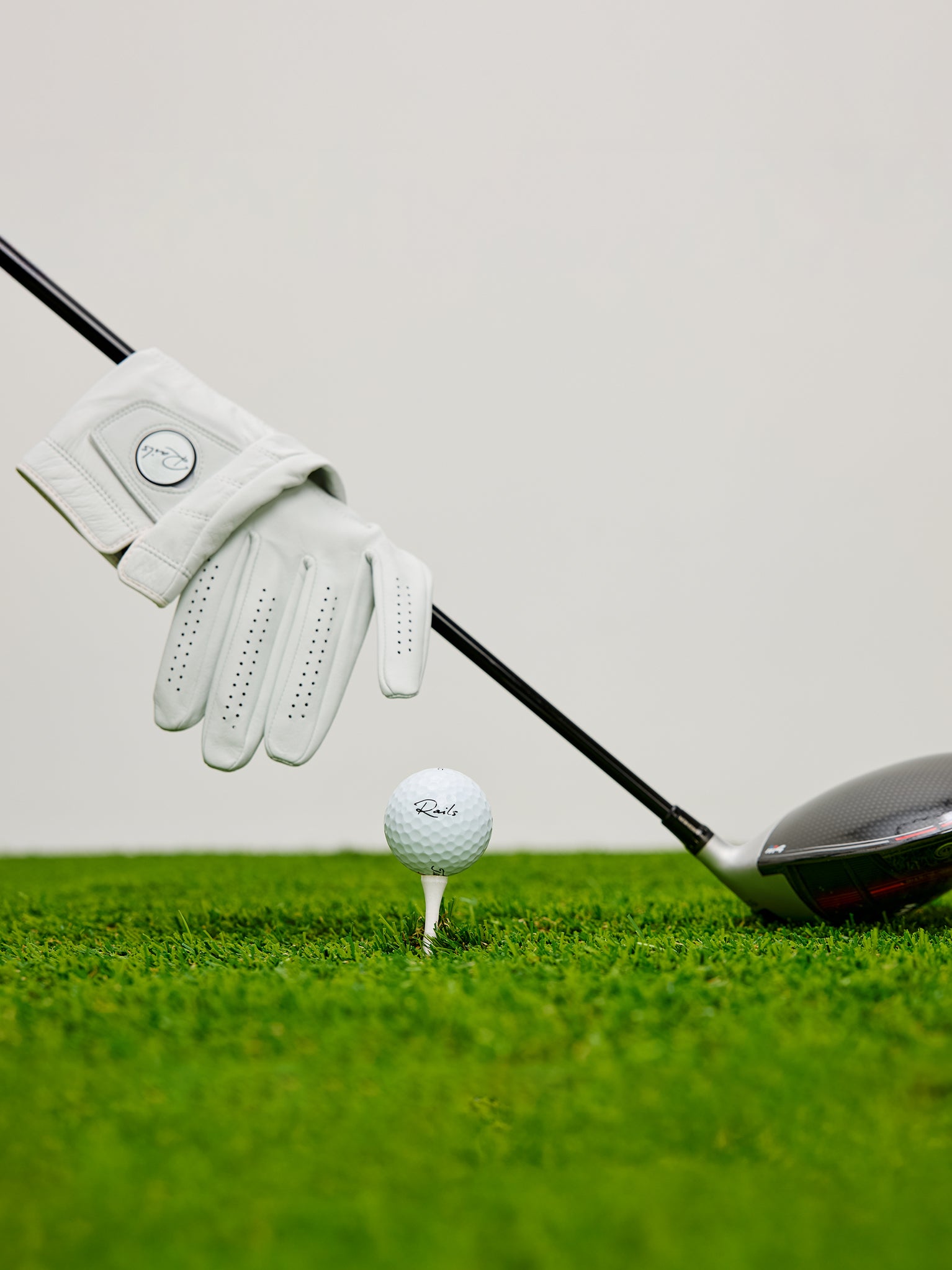 Golf club, glove, and golf ball on a green surface with a white background