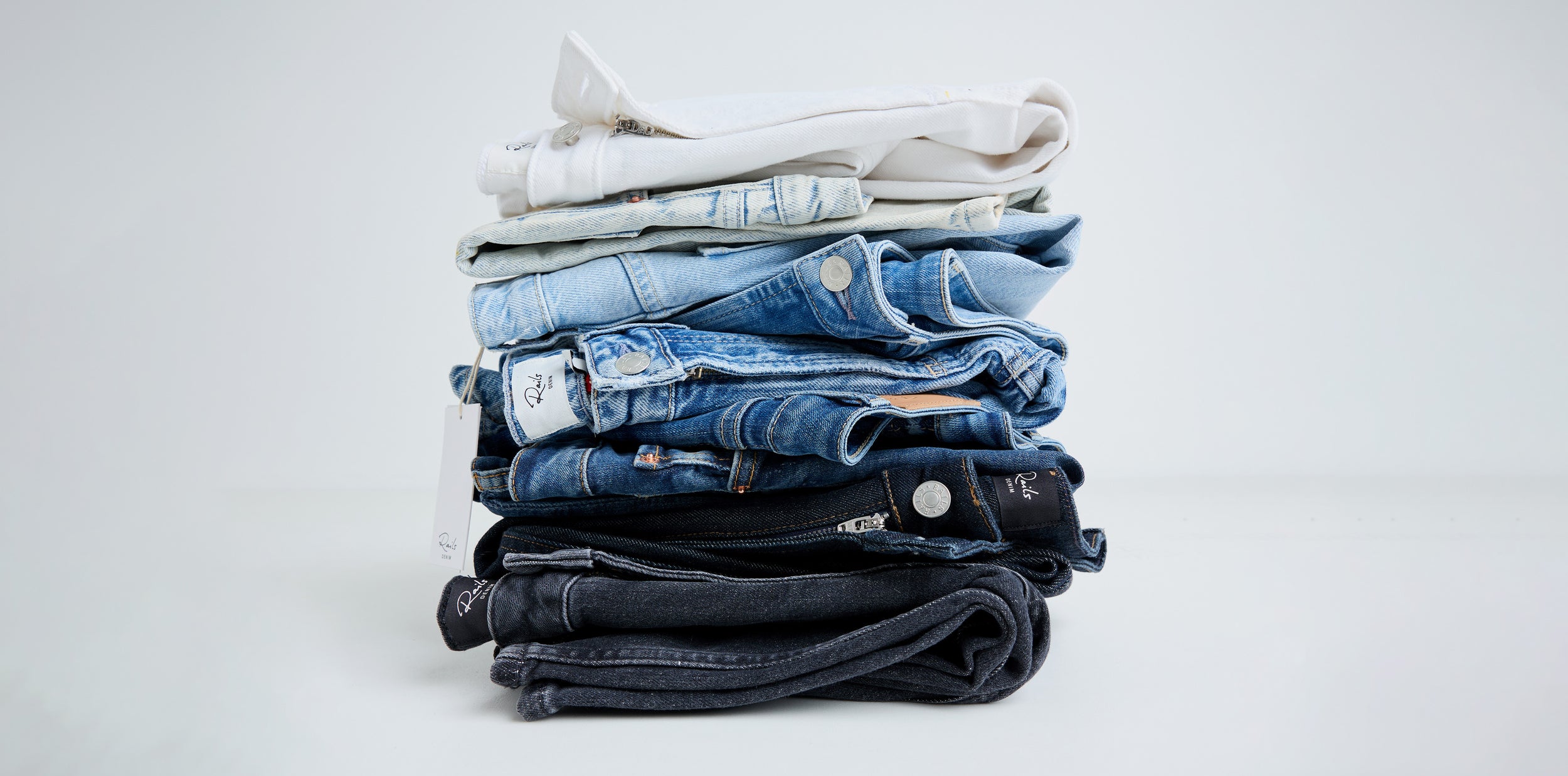 Stack of folded jeans on a light gray background