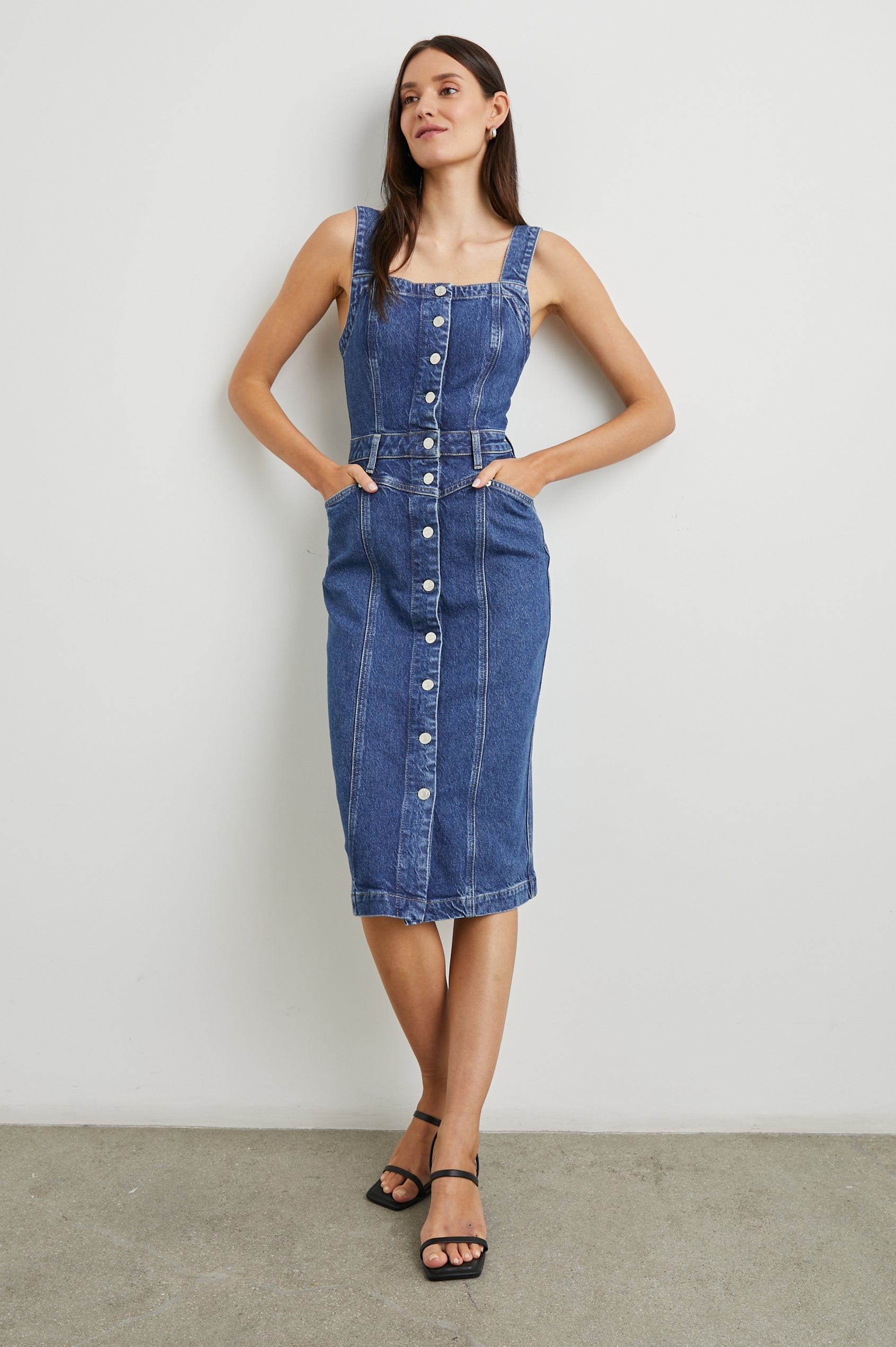 Malibu Sleeveless Denim Midi Dress with Shoulder Straps, Buttons Down the Front, a Square Neckline in the Front and Back, Two Front Pockets and Two Back Patch Pockets in Mazarine Colorway - Front Full Body View Featured on Model