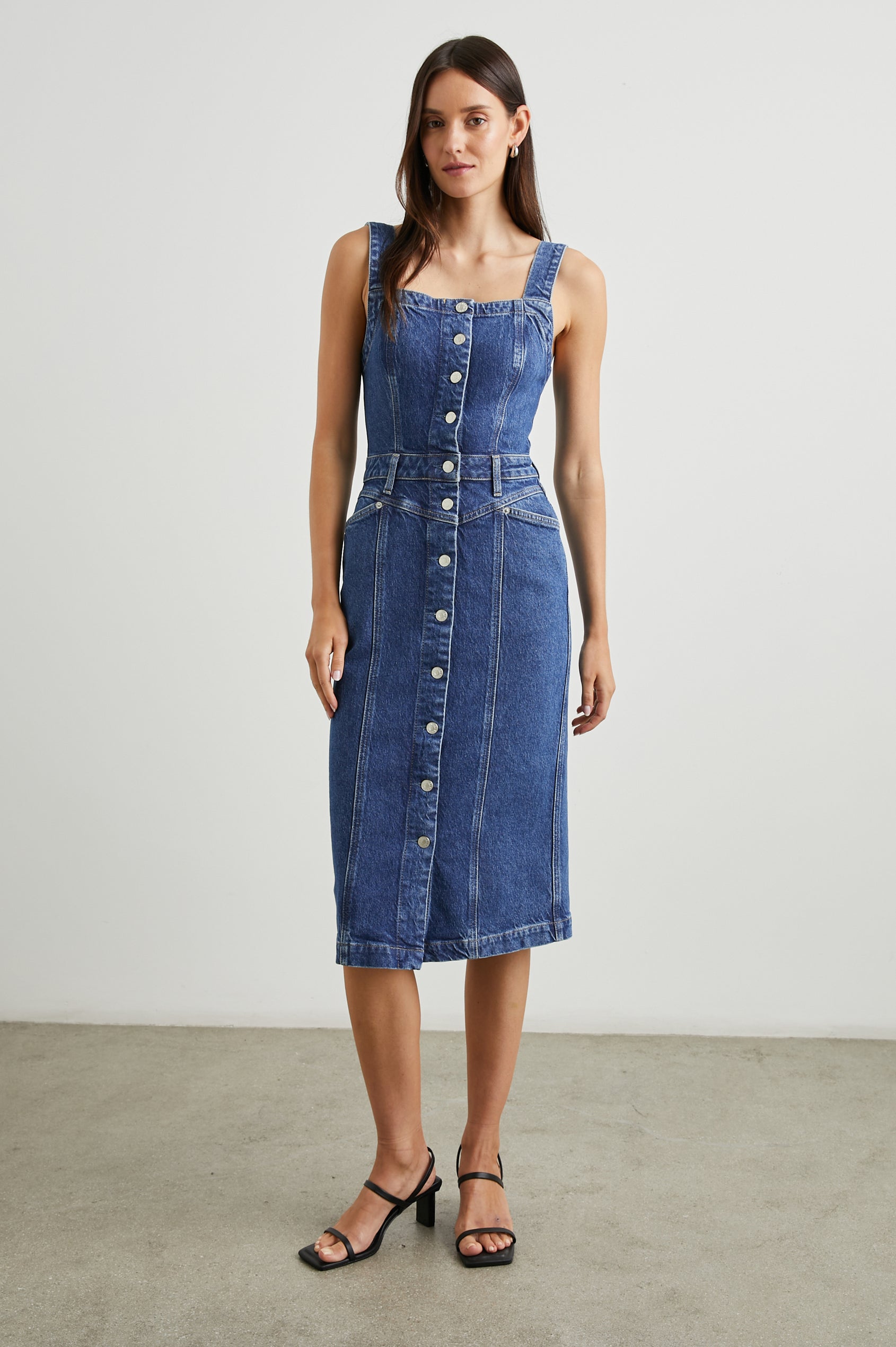 Malibu Sleeveless Denim Midi Dress with Shoulder Straps, Buttons Down the Front, a Square Neckline in the Front and Back, Two Front Pockets and Two Back Patch Pockets in Mazarine Colorway - Front Full Body View Featured on Model