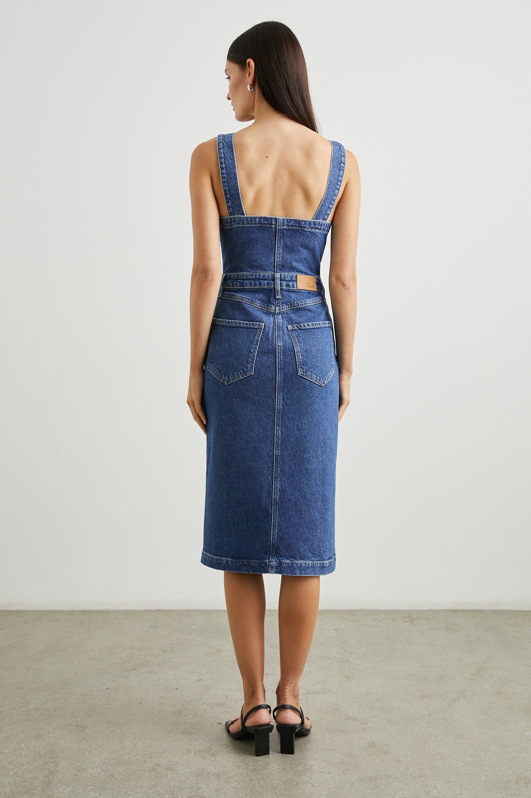 Malibu Sleeveless Denim Midi Dress with Shoulder Straps, Buttons Down the Front, a Square Neckline in the Front and Back, Two Front Pockets and Two Back Patch Pockets in Mazarine Colorway - Back Full Body View Featured on Model