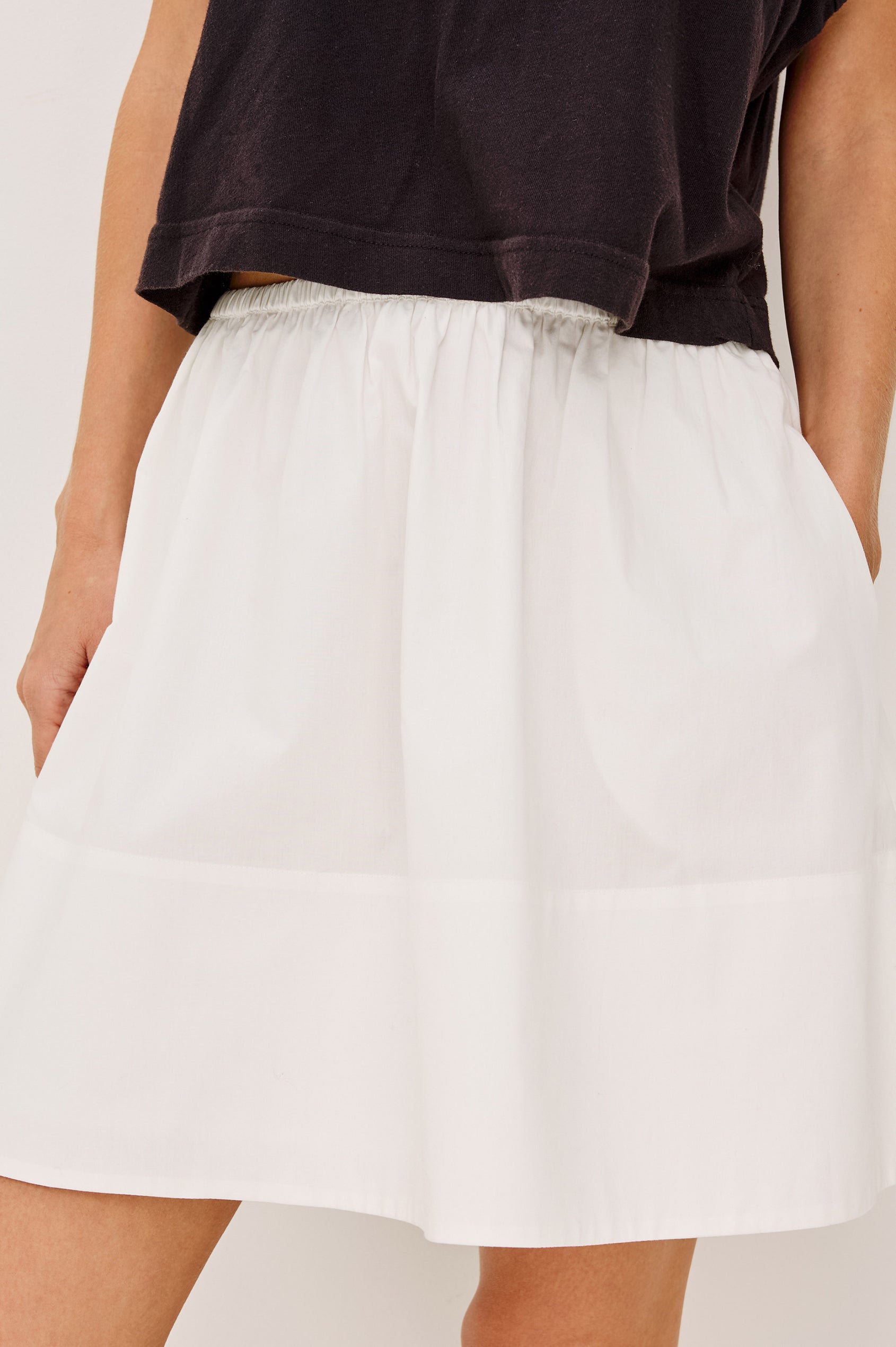 Margot Tennis Skirt in Cotton Poplin With Mid-Rise Elastic Waist, Side Pockets, and is Fully Lined in White Colorway - Lower Body Front View Featured on Model