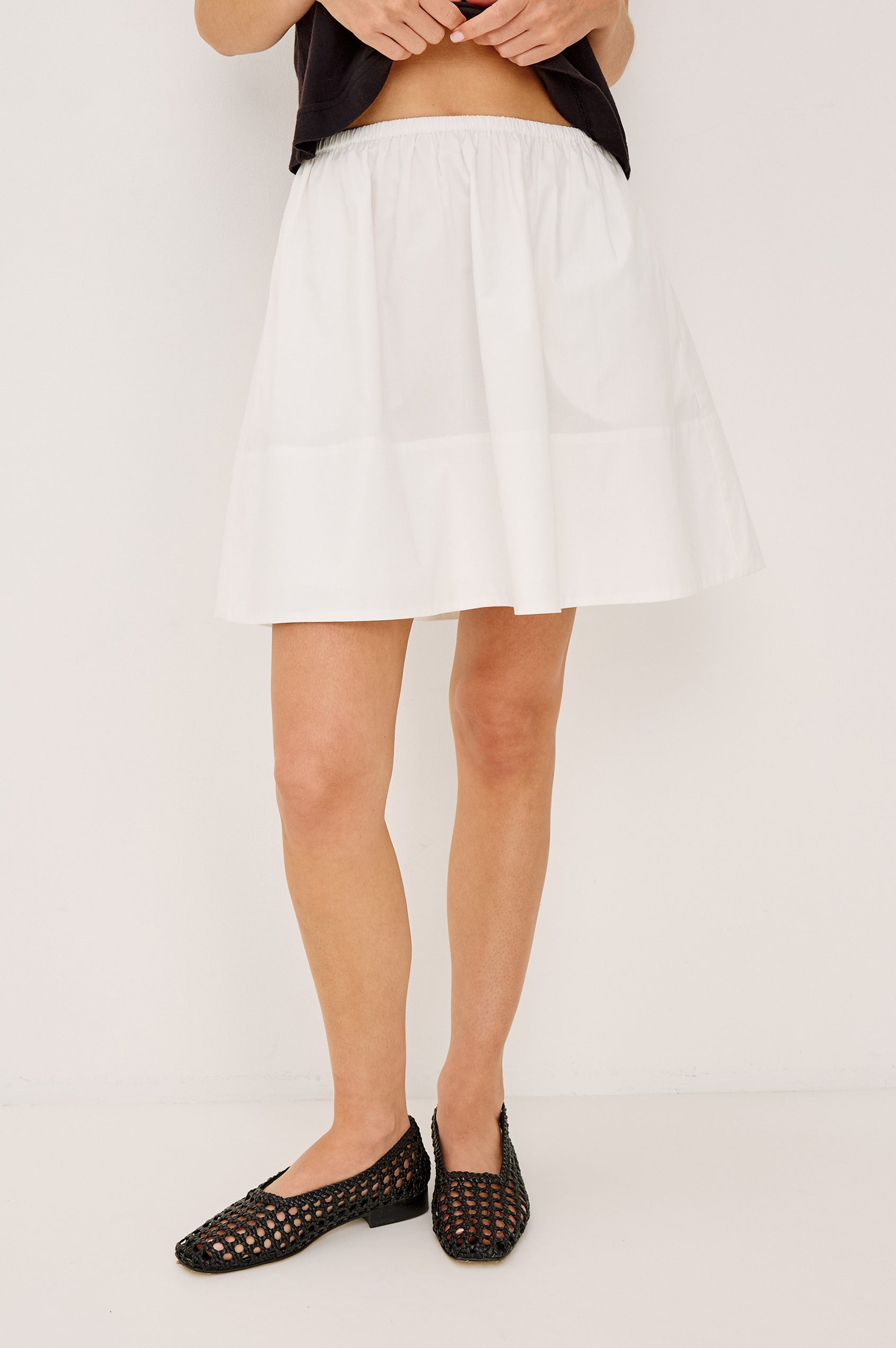 Margot Mini Skirt in Cotton Poplin With Mid-Rise Elastic Waist, Side Pockets, and is Fully Lined in White Colorway - Lower Body Front View Featured on Model