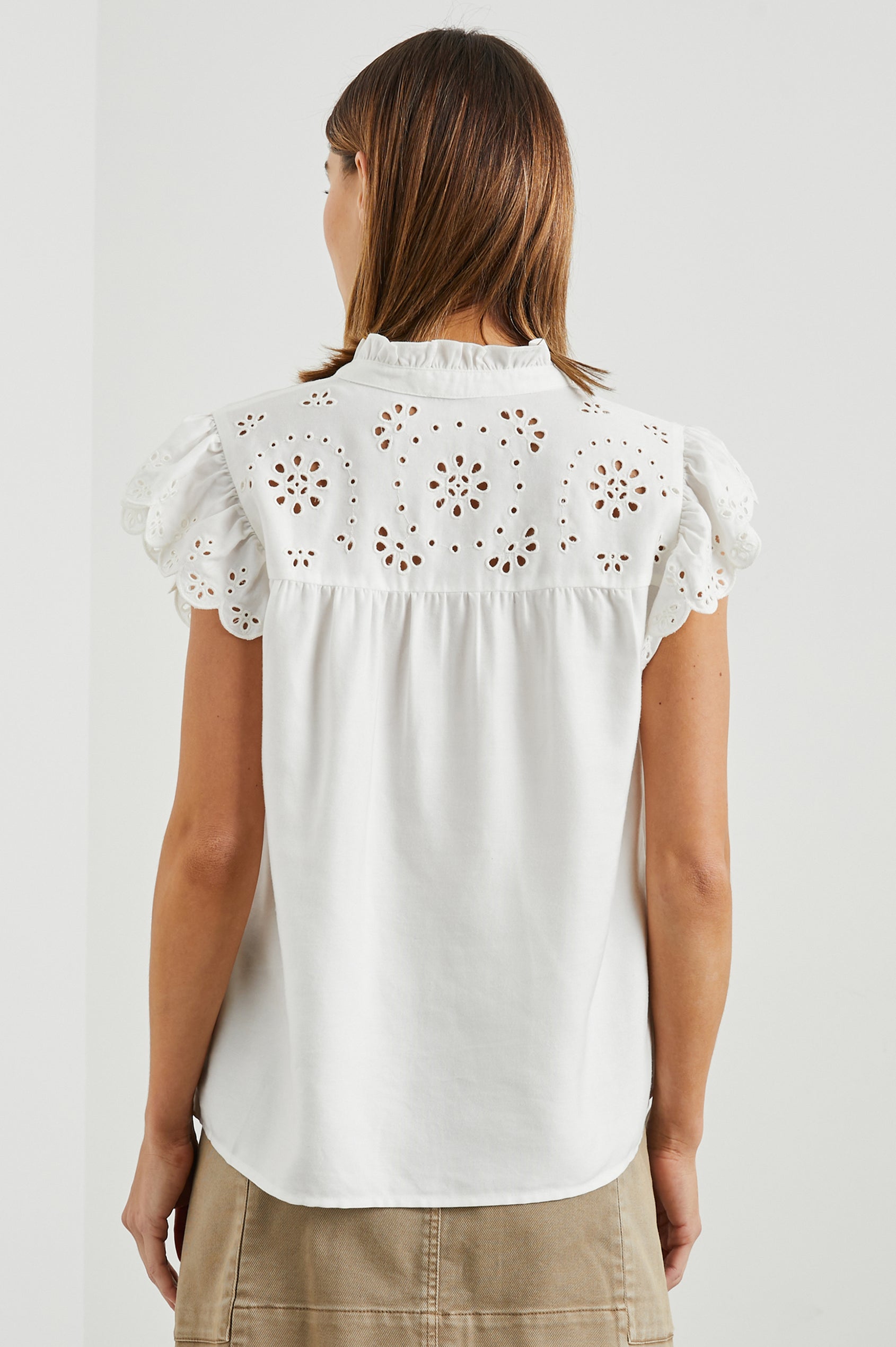 Marlene Short-Sleeve Button Up with Flutter Sleeves, Floral Eyelets on the Yoke and Sleeves, and Light Ruching along the Yoke Seams in White Denim Colorway - Back View Featured on Model 