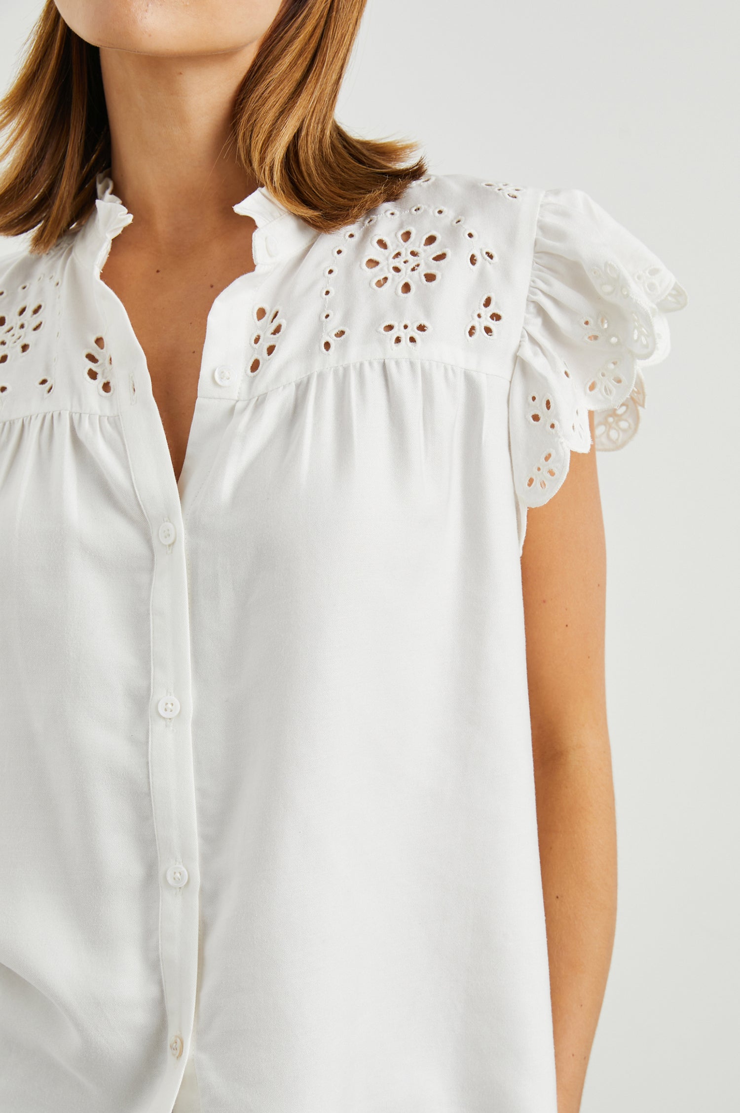 Marlene Short-Sleeve Button Up with Flutter Sleeves, Floral Eyelets on the Yoke and Sleeves, and Light Ruching along the Yoke Seams in White Denim Colorway - Front View Featured on Model 
