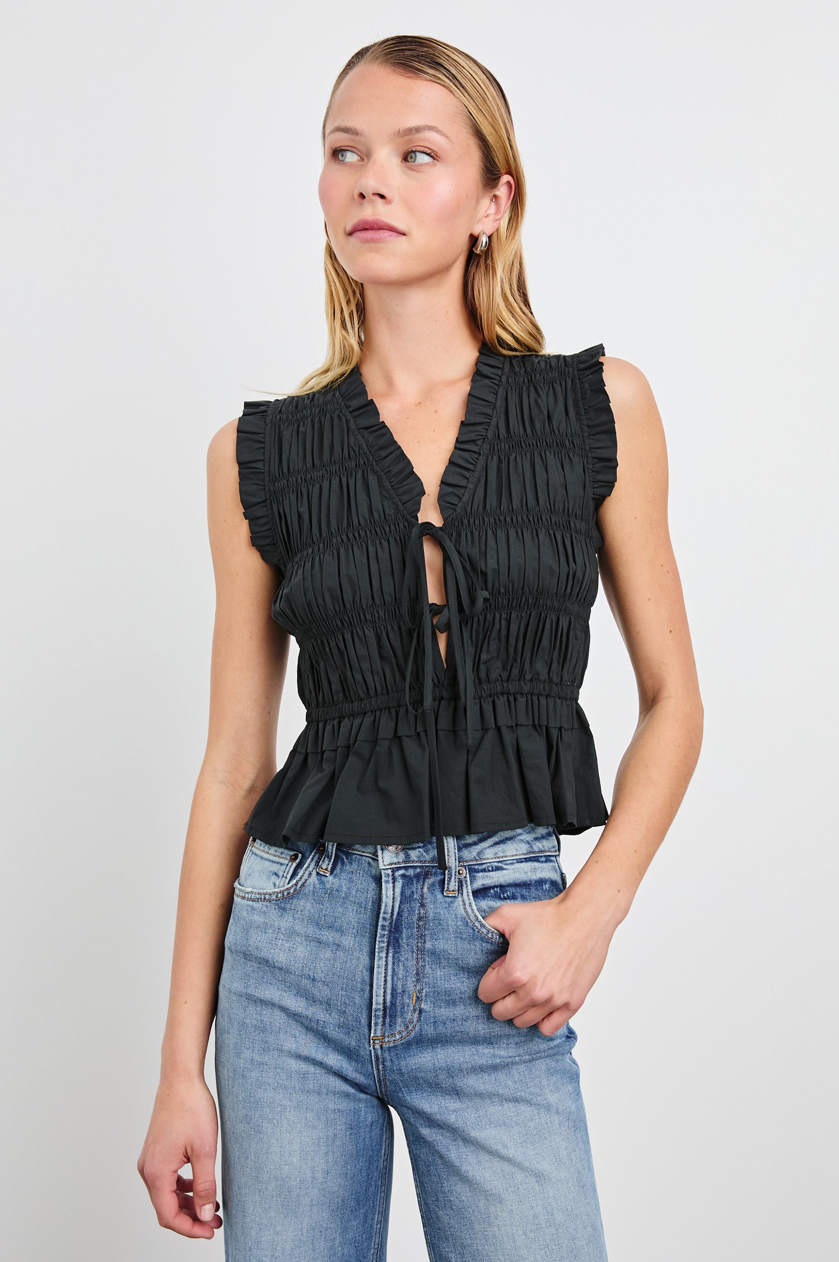 Martine Sleeveless Top with Ruffled Trim, a Deep V-Neck with Ties and Smocking in Black Colorway - Front View Featured on Model 