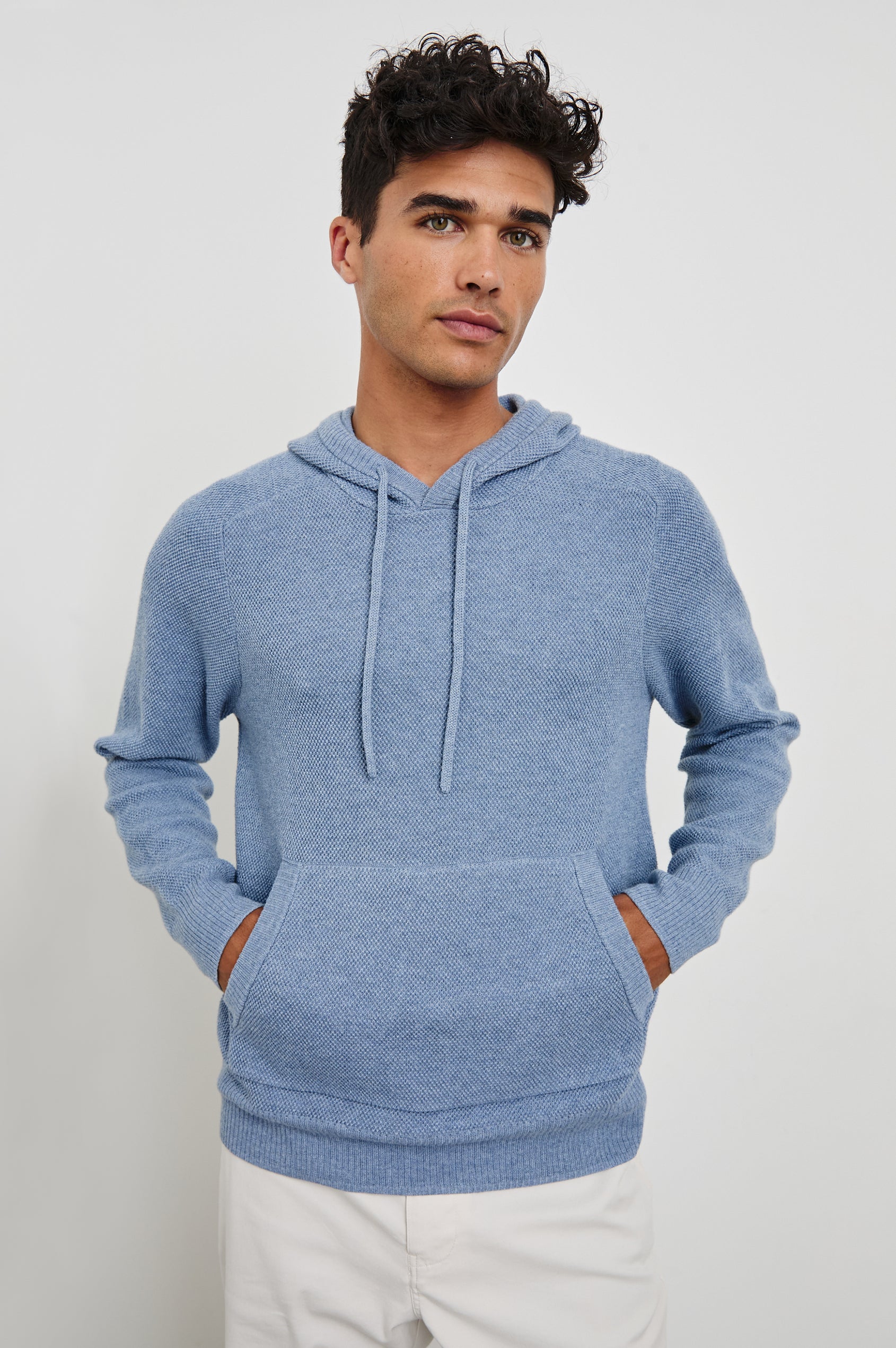 Matador knit sweater with hoodie, adjustable drawstrings, and dual side front pocket in Light Blue Heather - front view on model, hands in pocket
