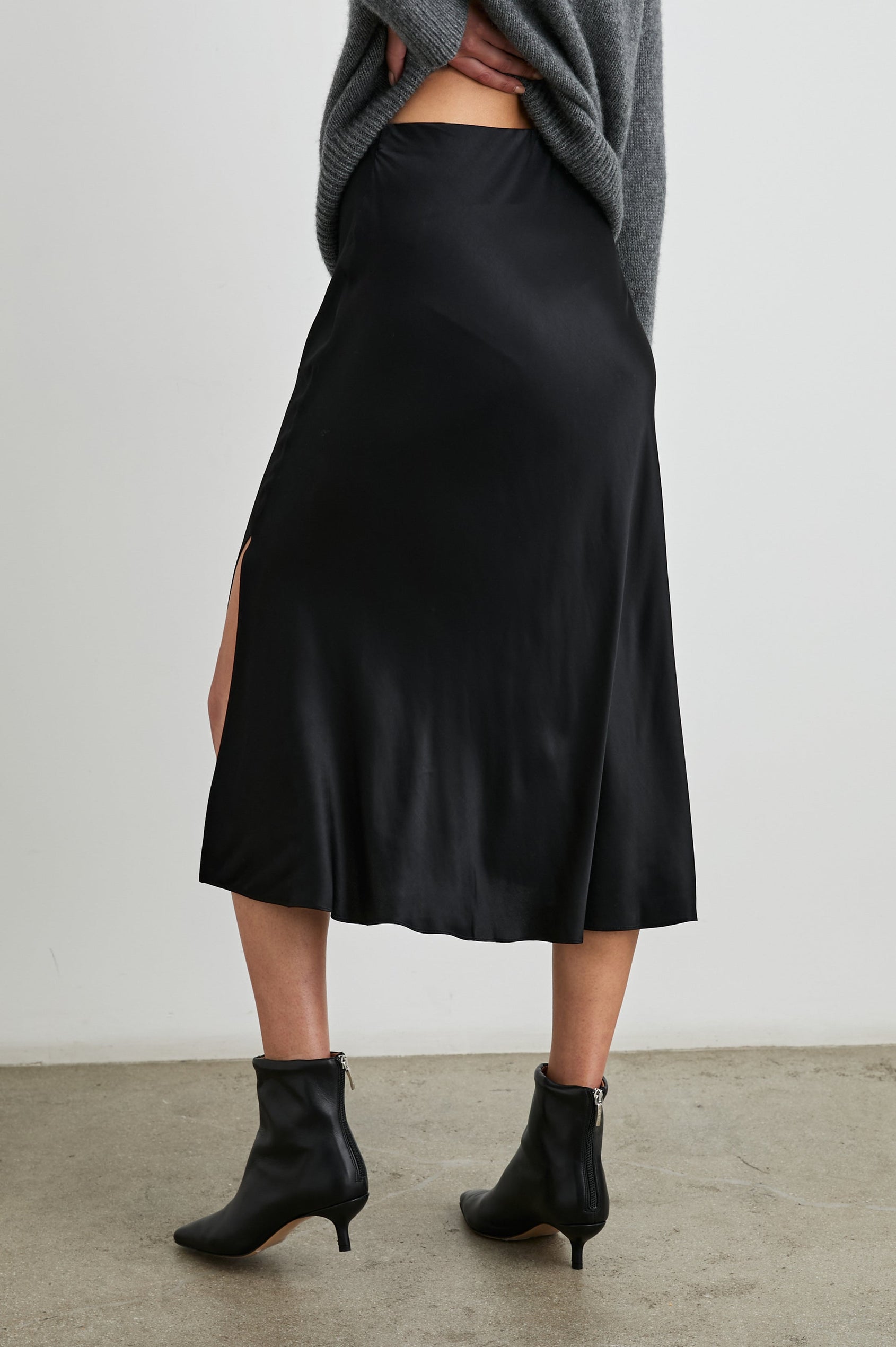 Maya Midi Skirt with Mid-Thigh Side Slit in Black Colorway - Back View Featured on Model