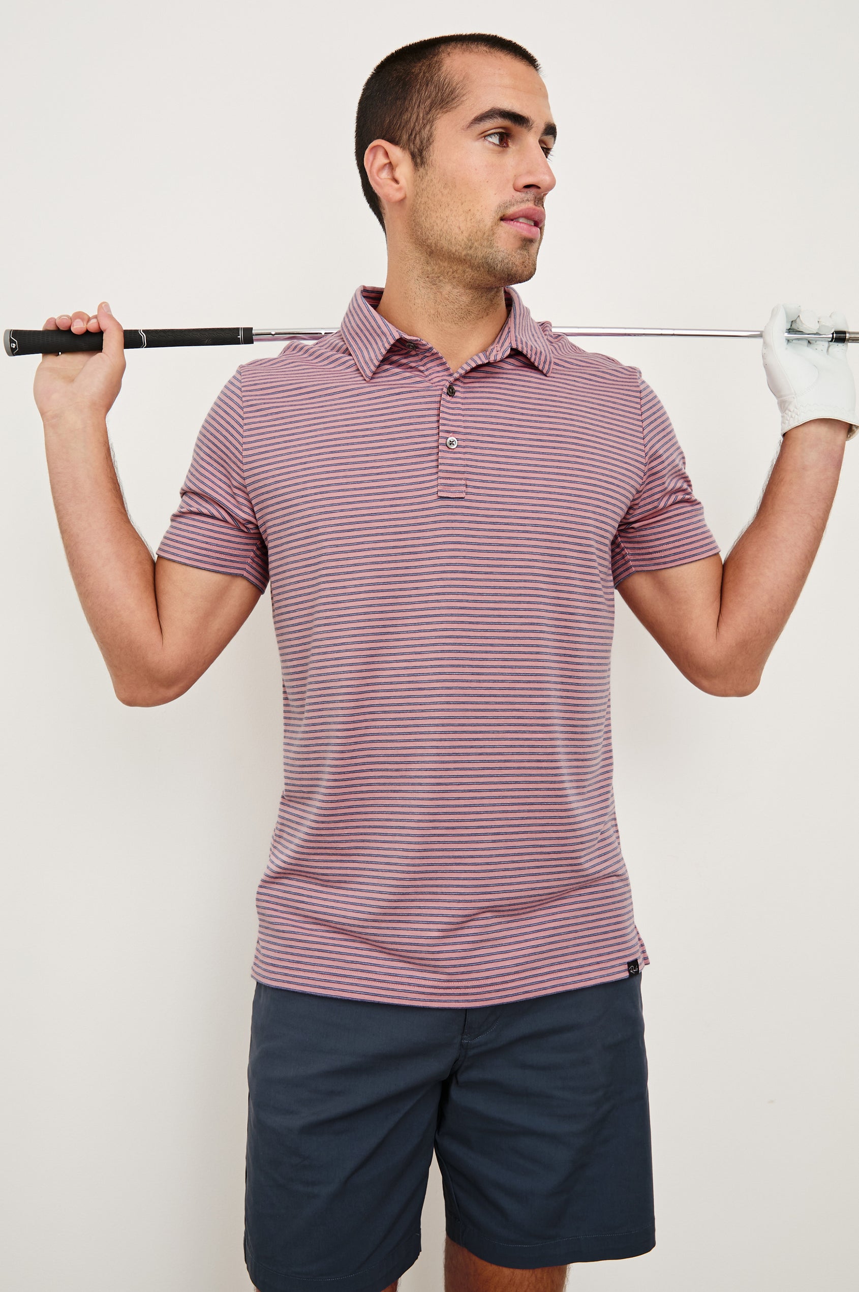 Merced short sleeve athletic Golf Polo with two button placket and collar in Hibiscus Mirage Stripe - front view on model holding golf club