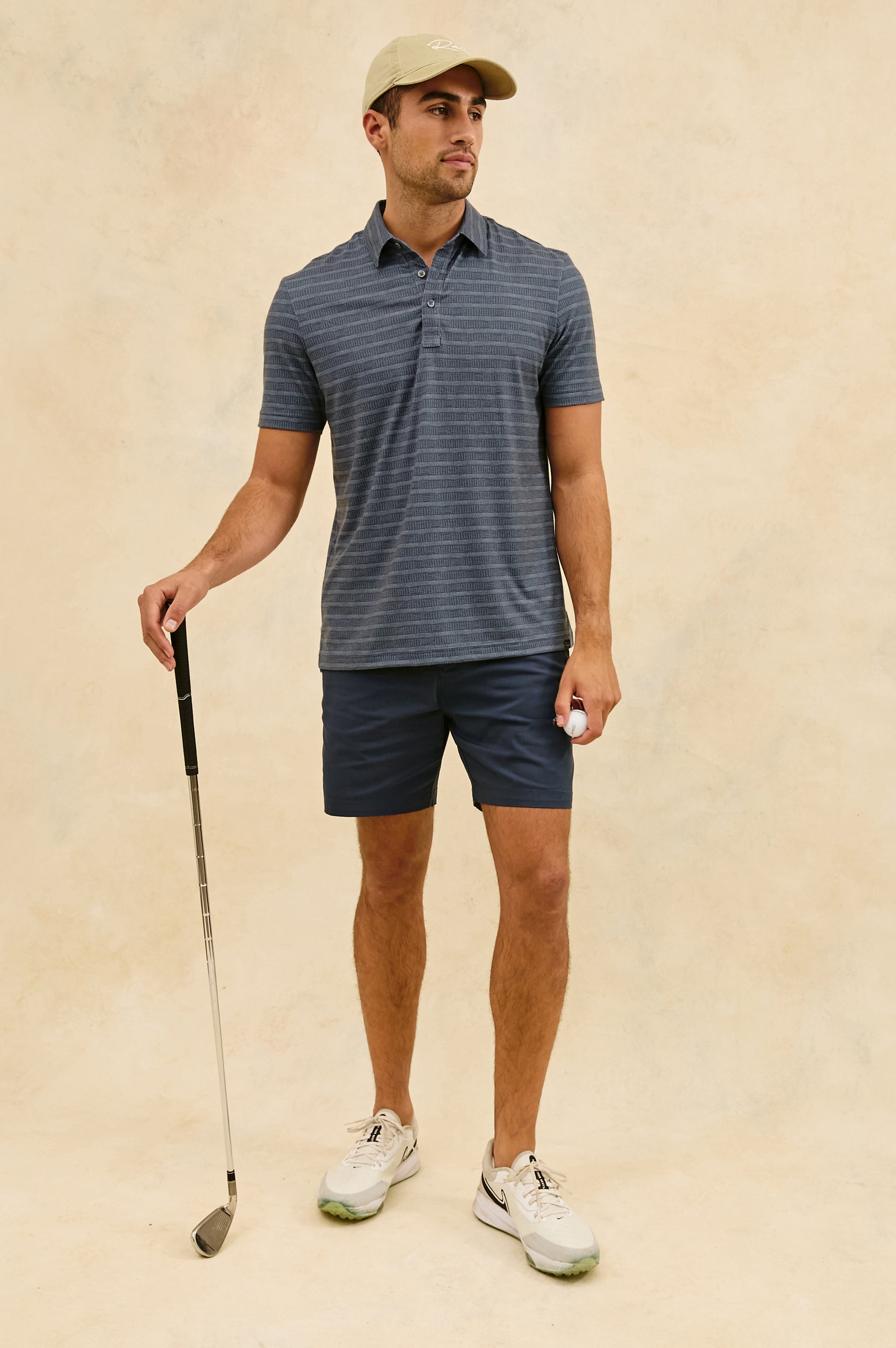 Merced short sleeve athletic Golf Polo with two button placket and collar in Sashiko Border Black - full body front view, model holding golf club and ball