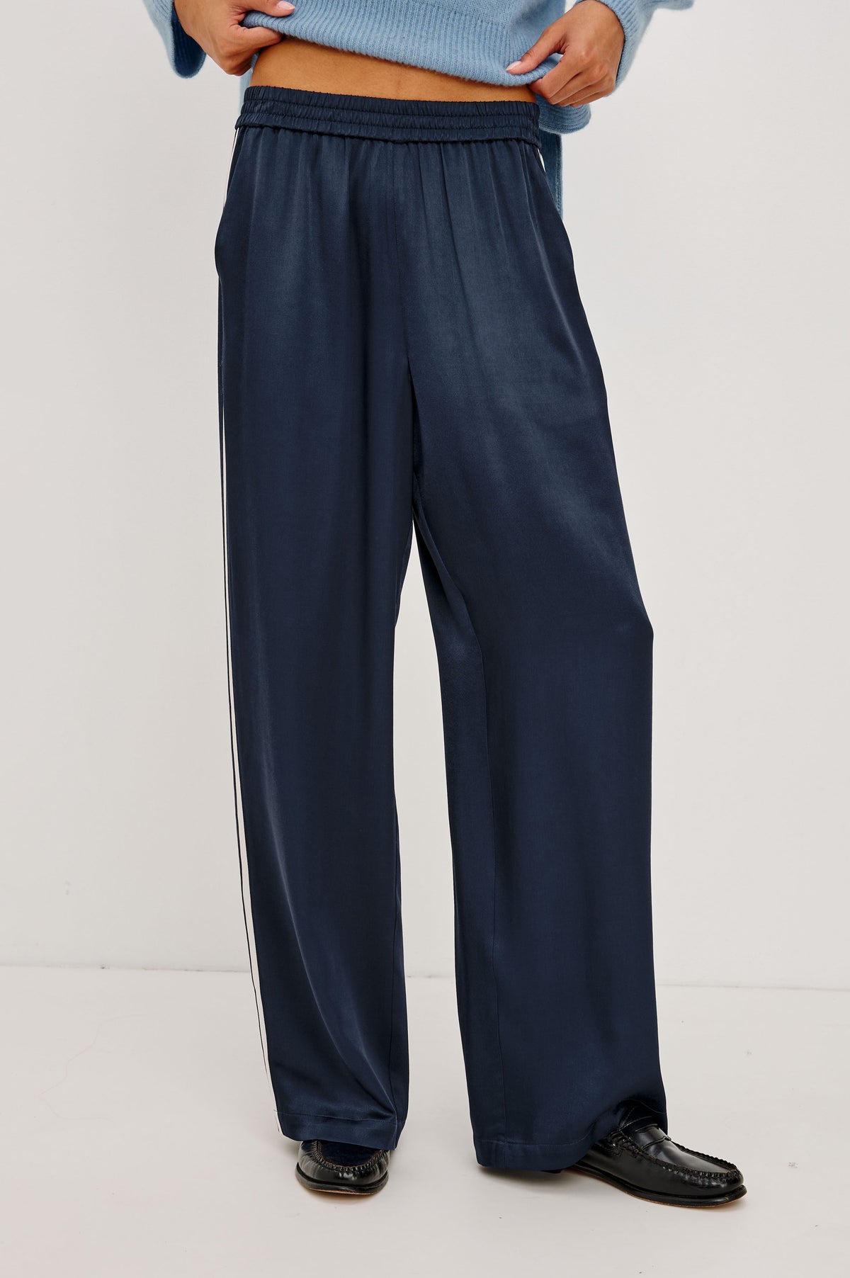 Merida Track Pant in Satin-Back Crepe With Elastic Waist, Side Slant Pockets, Wide Legs, and Contrast Side Stripes in Navy Colorway - Front Crop View Featured on Model.