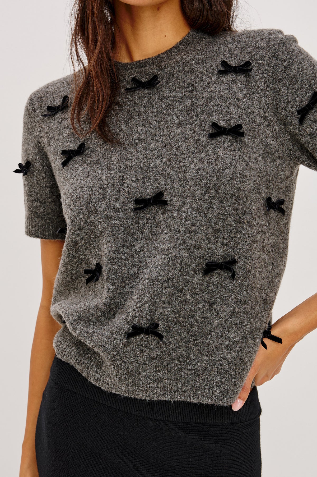 Michele Sweater in Wool Blend With an Off-The-Shoulder Neckline and Bow Applique in Charcoal Colorway - Front Crop Detail View Featured on Model.