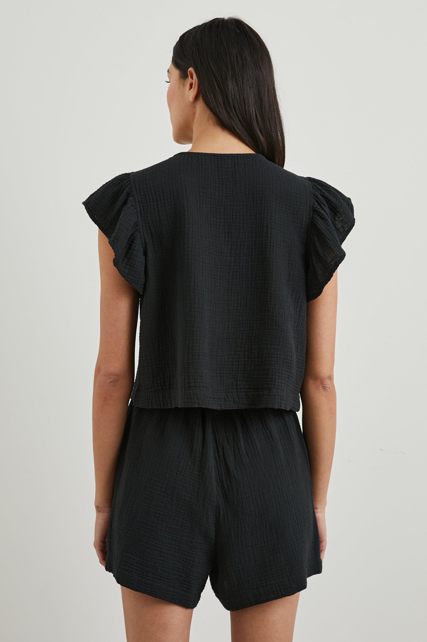 Miley Cropped, Short-Sleeve, V Neck Top with Flutter Sleeves and Textured Fabric in Black Colorway - Back View Featured on Model