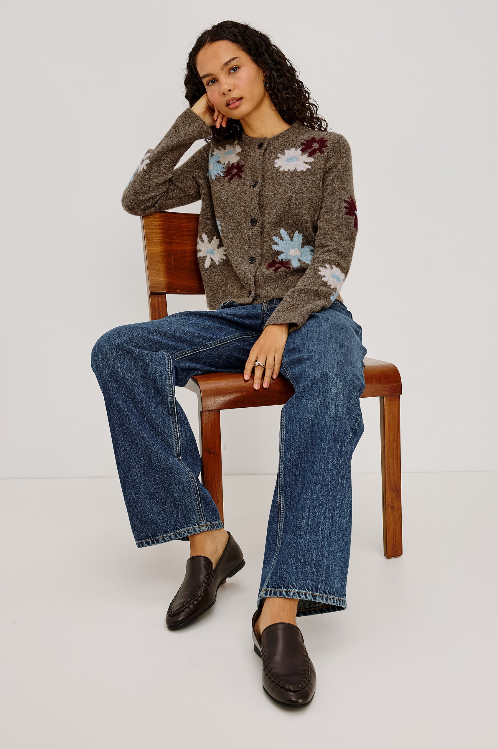 Millie Cardigan in Wool Blend Knit With Slightly Cropped Relaxed Fit, Crew Neck, Front Buttons, Long Sleeves, and Ribbed Trim in Grey Flora Colorway - Full Body View Featured on Model Sitting