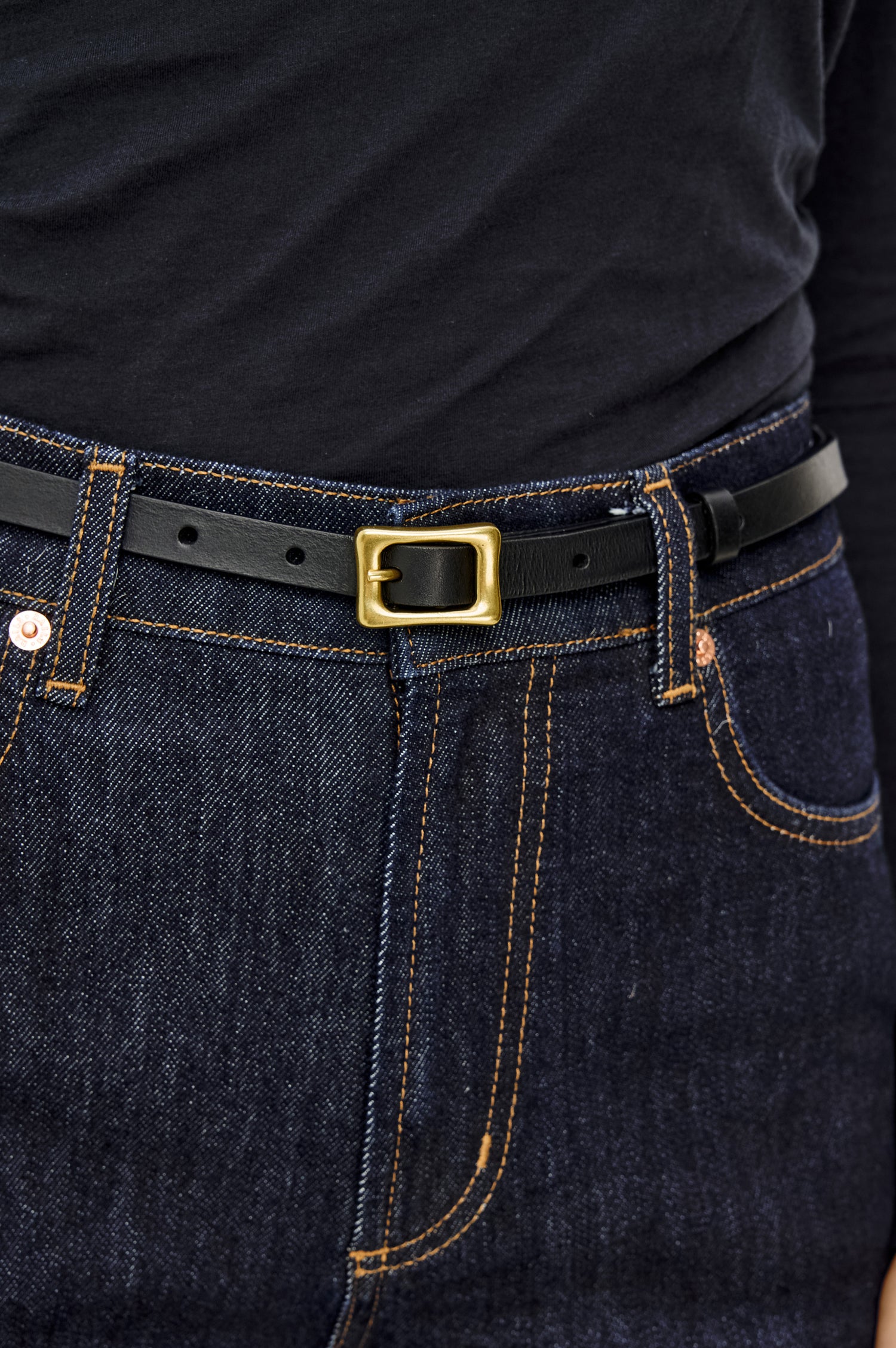 Remi Slim Leather Belt With Adjustable Buckle Closure in Black Gold Colorway - Close Up Front Mid Body View Featured on Model