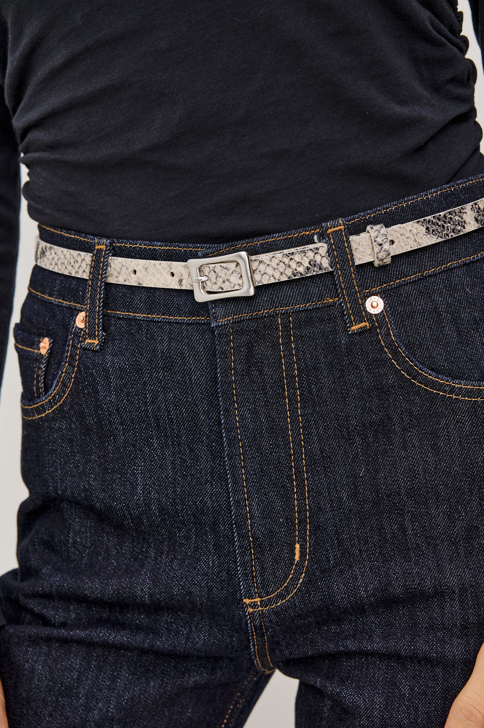 Remi Slim Leather Belt With Adjustable Buckle Closure in Ecru Python Colorway - Close Up Front Mid Body View Featured on Model