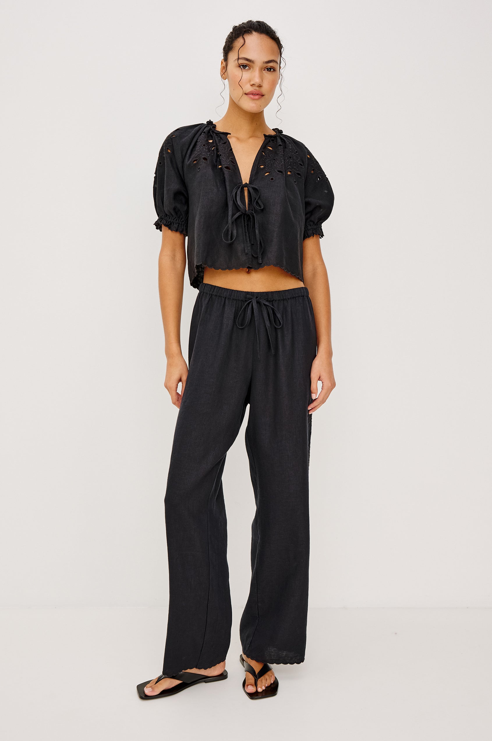 Made from midweight linen the Mirina Pant has an elastic waistband with adjustable center front ties side pockets loose straight legs and intricate floral cutwork and scalloped trim.