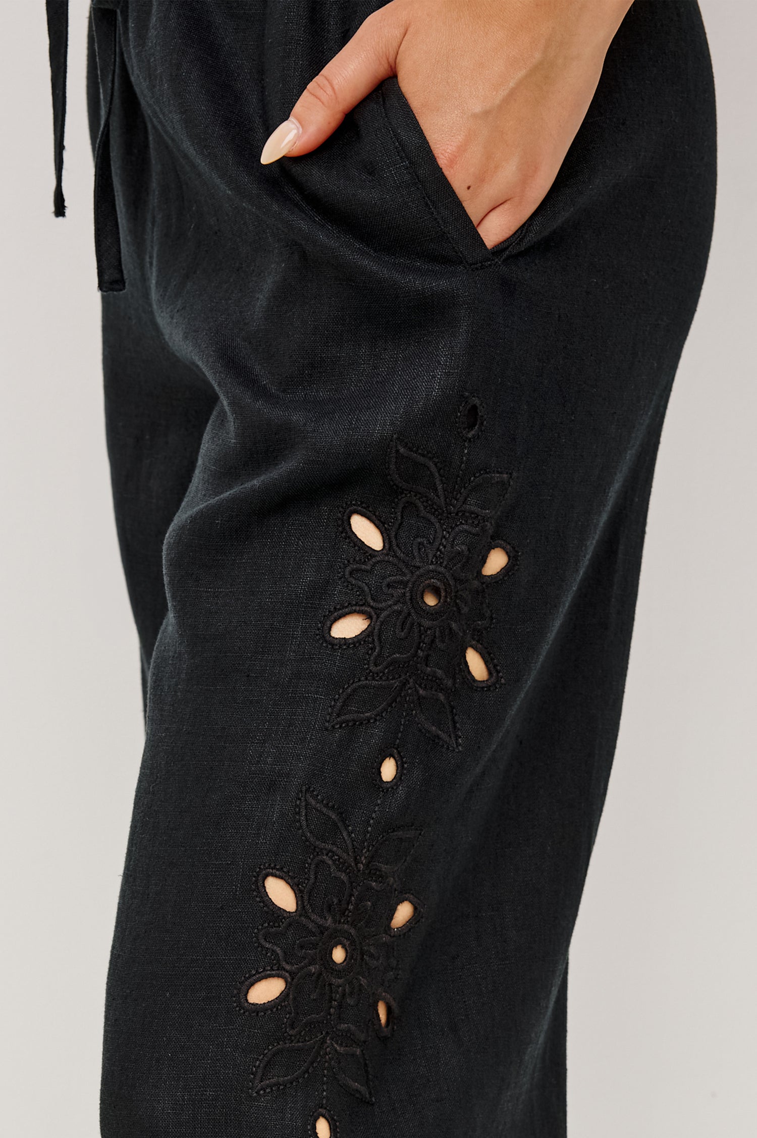 Made from midweight linen the Mirina Pant has an elastic waistband with adjustable center front ties side pockets loose straight legs and intricate floral cutwork and scalloped trim.