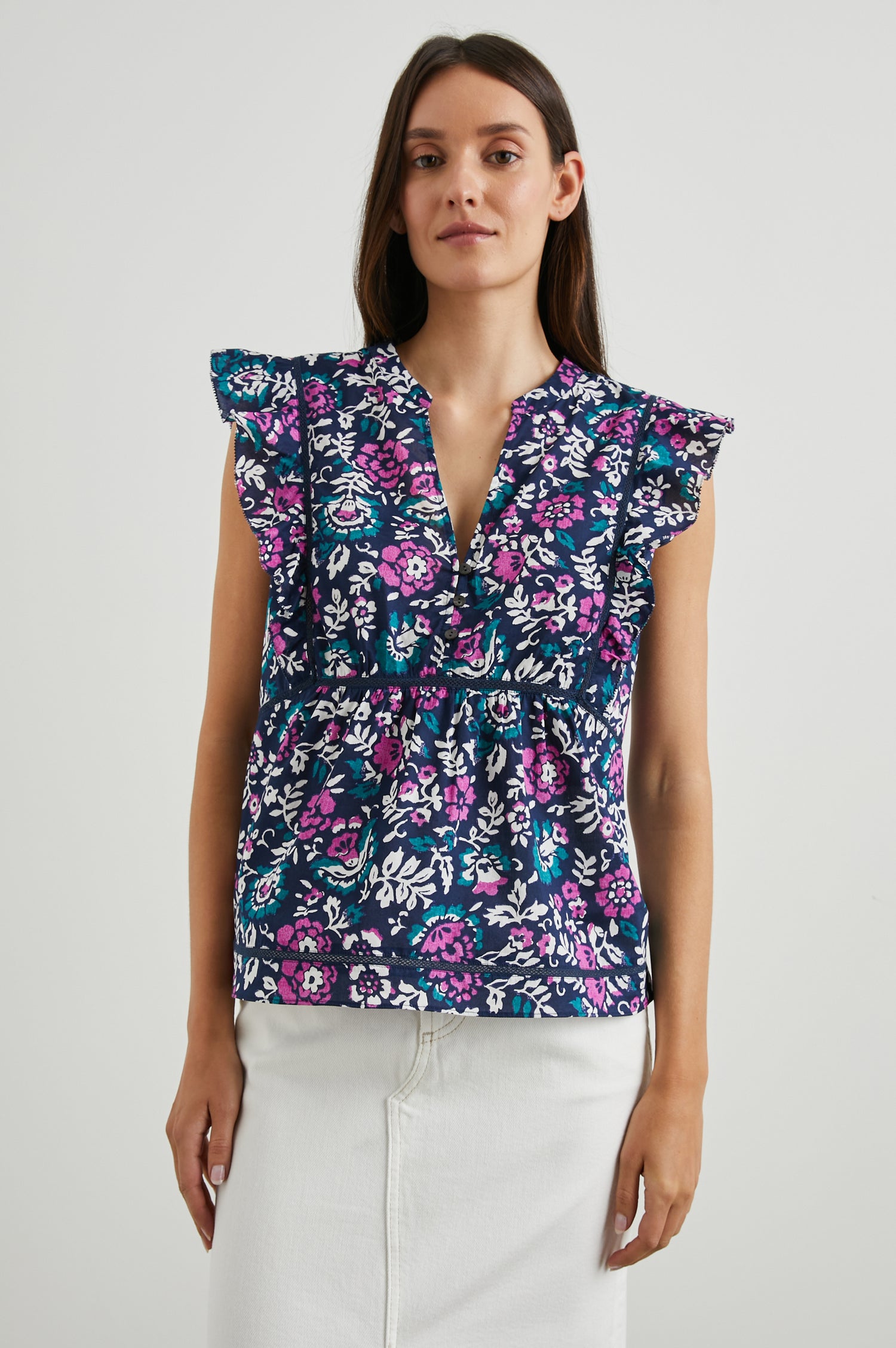 Misha Short Sleeve Top with Flutter Sleeves, a Deep V Neck, and Vertical and Horizontal Black Seams in Woodblock Floral Colorway, Pink, White and Green on Navy - Front View Featured on Model 
