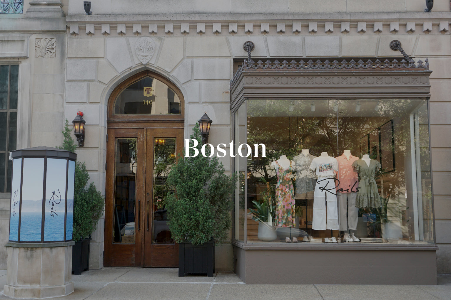 OUTSIDE OF BOSTON STORE SHOWING MAIN ENTRANCE (LARGE WOODEN DOOR) AND FRONT DISPLAY WINDOW (LARGE GLASS WINDOW WITH MULTIPLE MANIQUINS DISPLAYING CLOTHING)