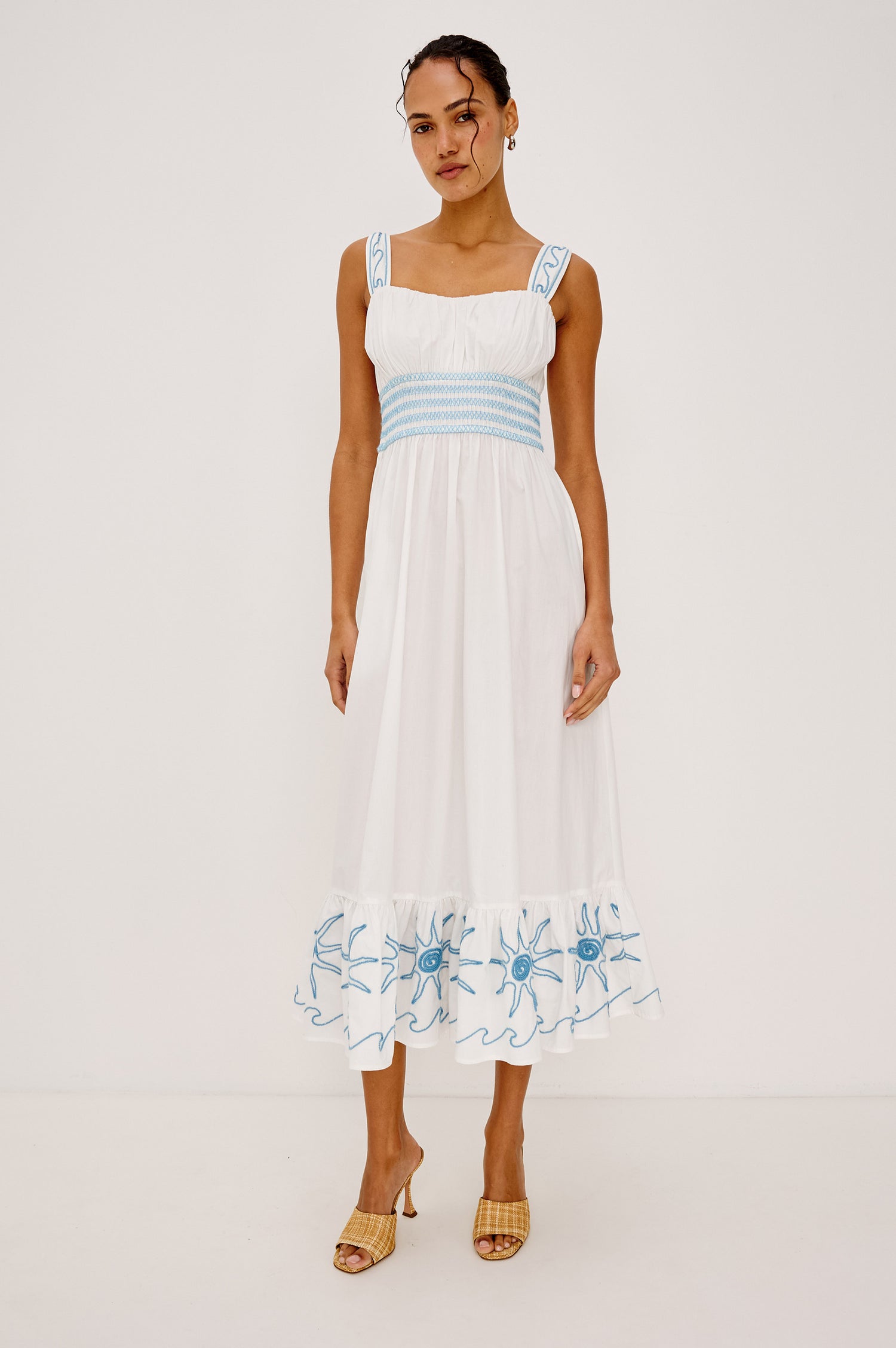 Moira Midi Dress in Cotton Poplin With Wide Embroidered Shoulder Straps Soft Sweetheart Neckline Smocked Empire Waist Fully Lined Skirt With Floral Cutwork at Hem in a White Colorway With Blue Embroidery Details - Full Body Front View Featured on Model
