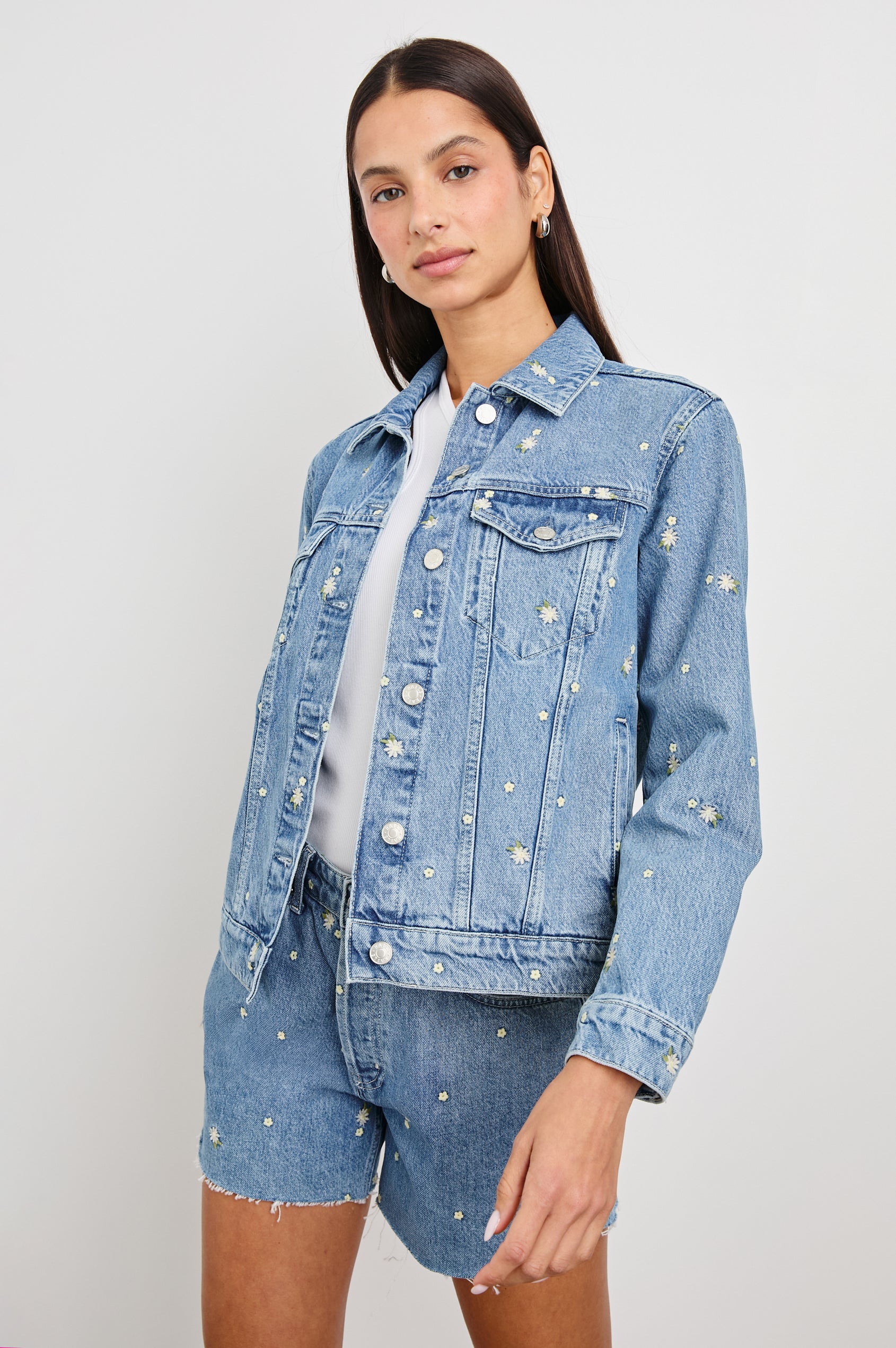Mulholland Indigo Trucker Style Denim Jacket with 2 Front Pockets, Front Buttons, and Daisy Embroidery Details - Front View On Model at a Slight Angle