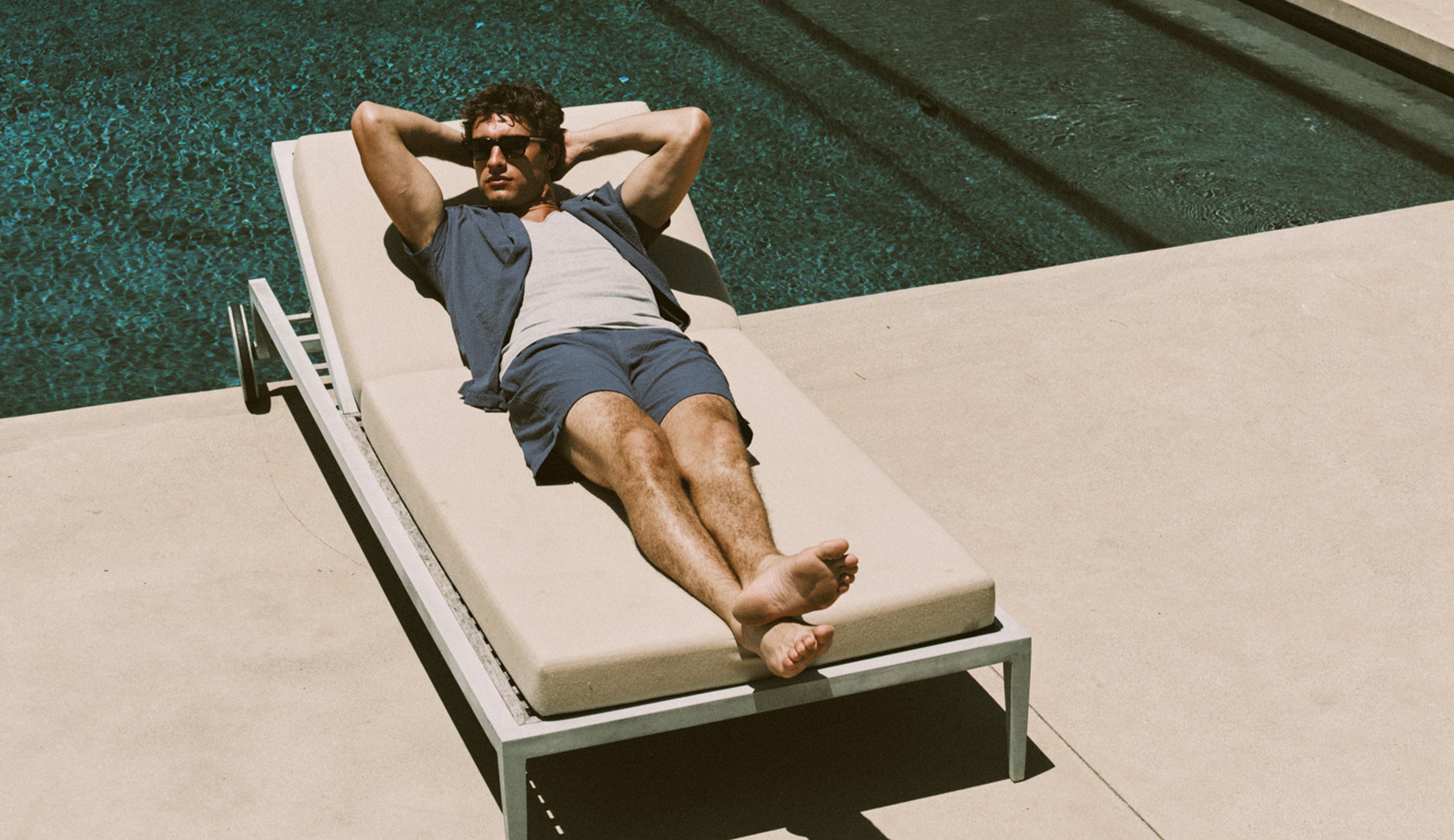 Man relaxing on a lounge chair by a pool