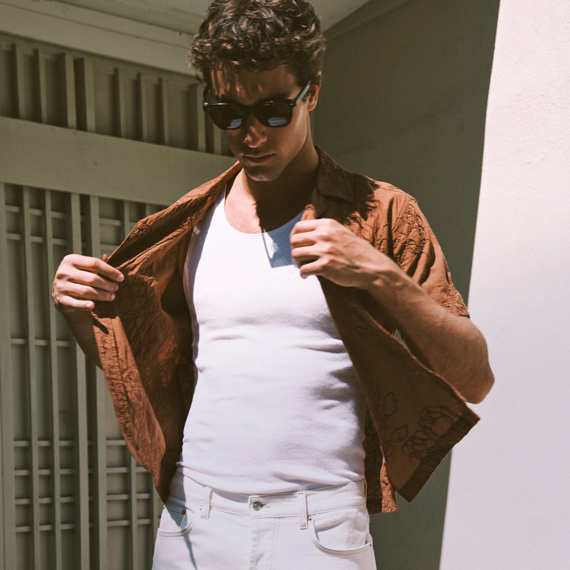 Man wearing a white tank under a brown button down shirt