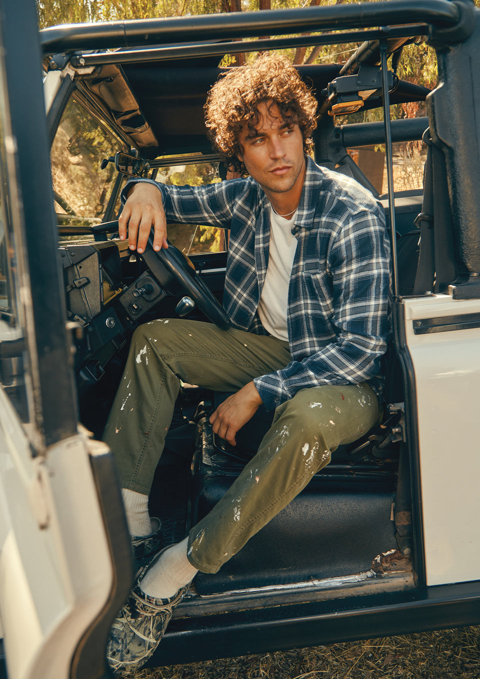 FRONT EDITORIAL IMAGE OF MODEL SITTING IN CAR WEARING LENNOX SHIRT AND JOHNNY T-SHIRT