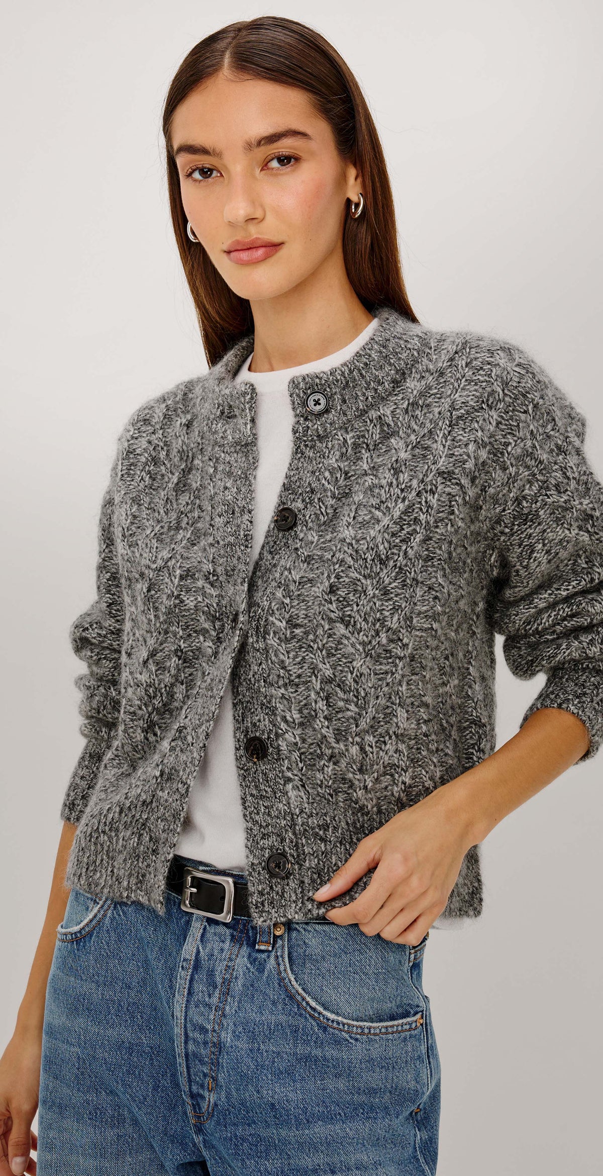 A woman wearing a gray textured knit cardigan over a white top and blue jeans, shown beside a close-up detail of the cardigan's button and knit texture.