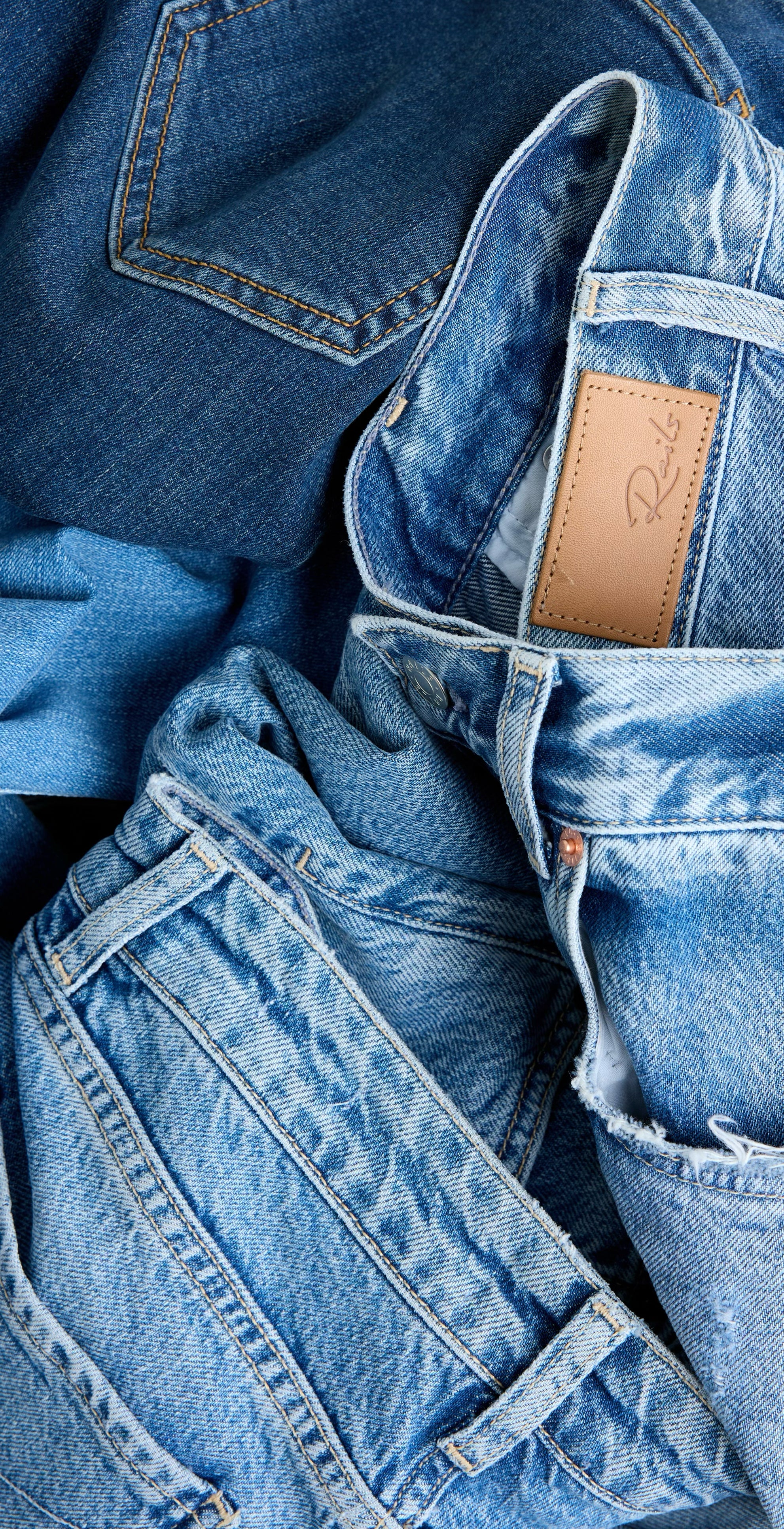 Stack of blue jeans with a brand label on a blue background