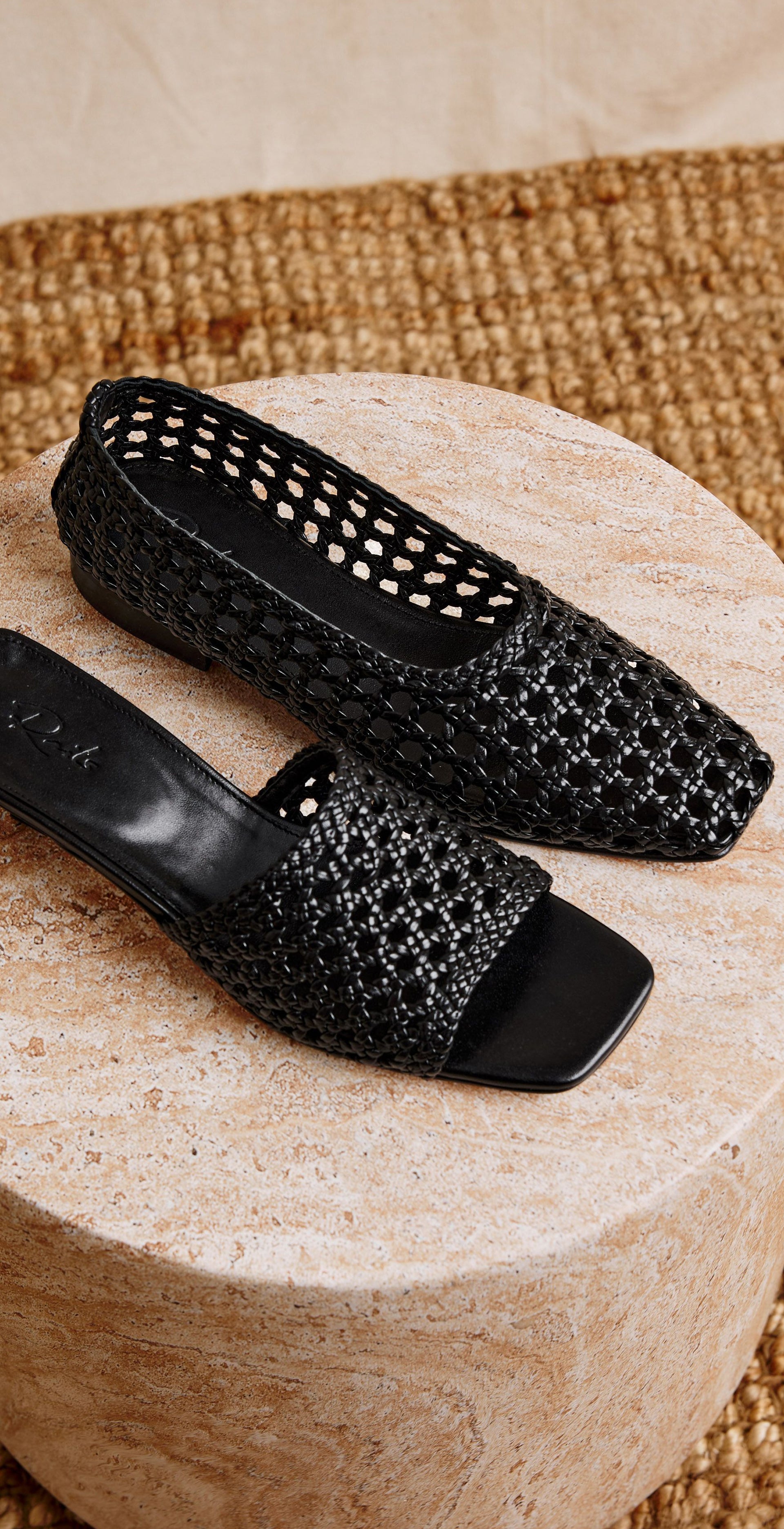 Image of two black woven shoes on a marble surface